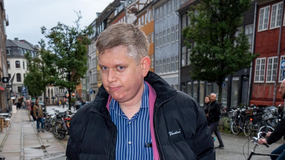 Rasmus Paludan ankommer til retten iført mørkeblå kappe og hat med hvid fjer – et outfit han selv beskriver som uniform for "Nordens Vogtere". Det er dog ikke tilladt at fotografere tiltalte ved retten. Her ses Paludan derfor ved en tidligere lejlighed.