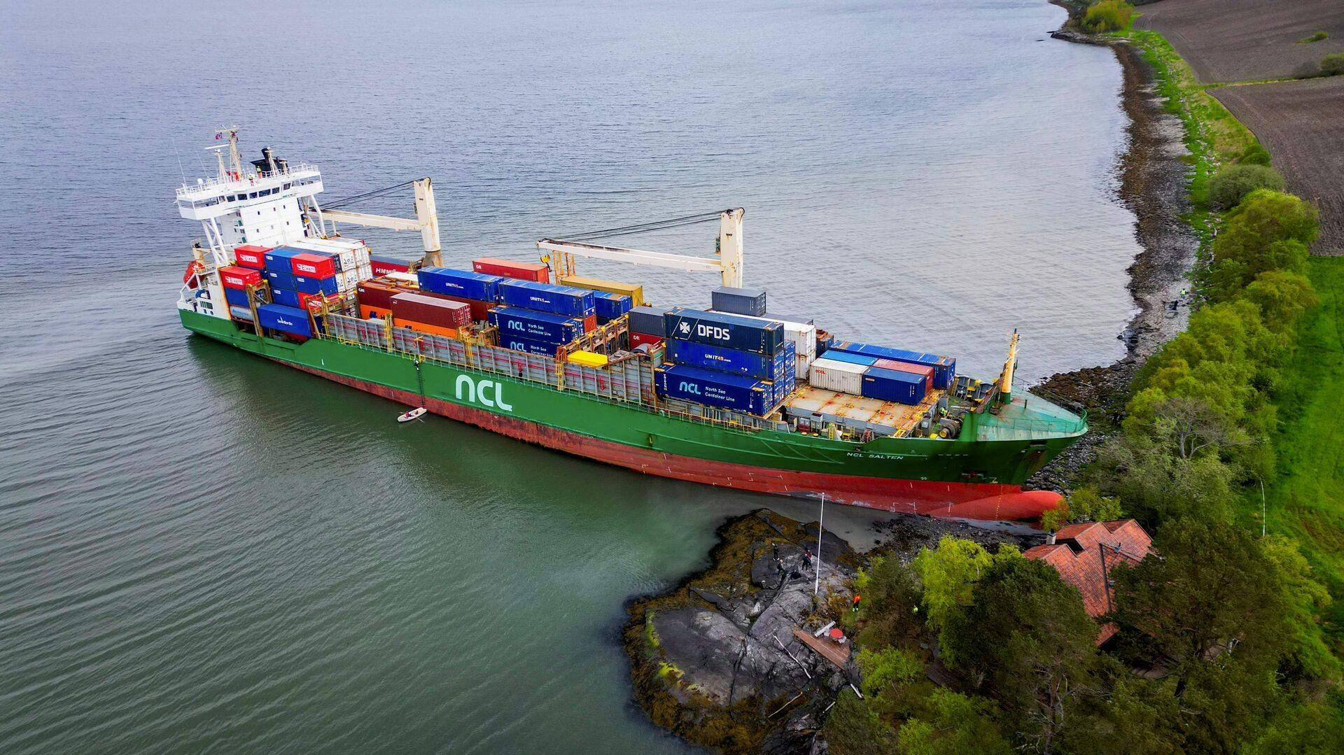 An areal view shows a 135-meter-long container ship by the shore in the Trondheimsfjord outside Byneset by Trondheim, Norway, on May 22, 2025, after it ran aground almost hitting a house. (Photo by Jan Langhaug / NTB / AFP) / Norway OUT