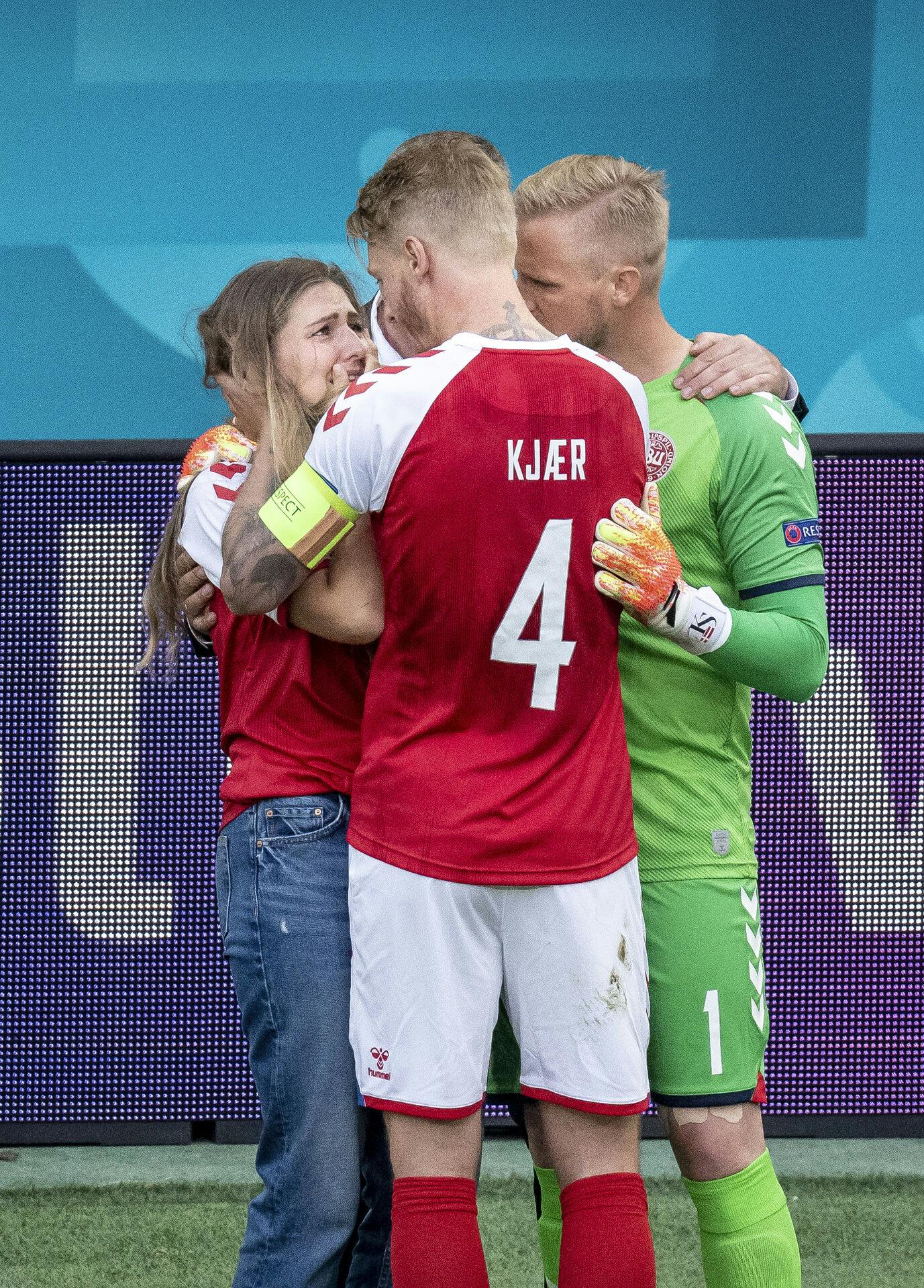 Danmarks Kasper Schmeichel og Simon Kjær trøster Sabrine Kvist Jensen imens at Danmarks Christian Eriksen får behandling under kampen mellem Danmark og Finland lødag den 21. juni 2021.