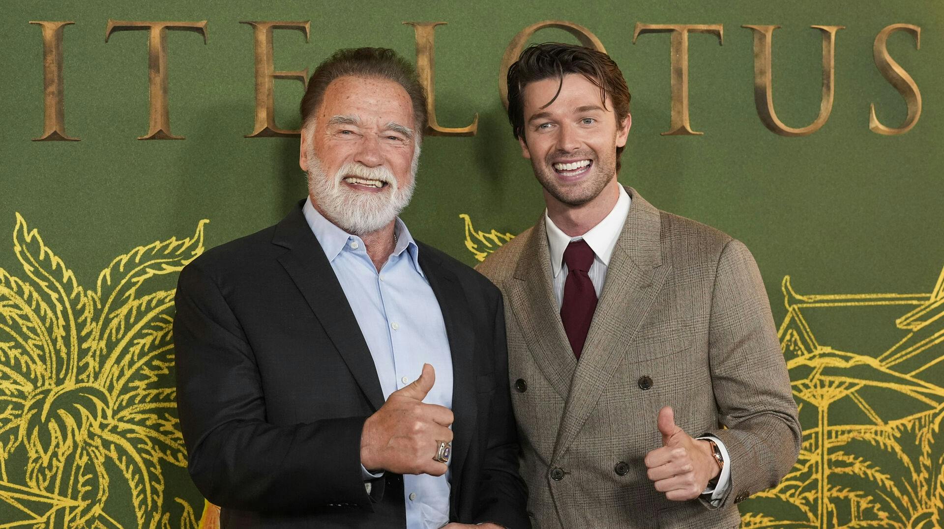 Arnold Schwarzenegger, left, and Patrick Schwarzenegger give the thumbs up at the season three premiere of "The White Lotus" on Monday, Feb. 10, 2025, at Paramount Theater in Los Angeles. (AP Photo/Chris Pizzello)
