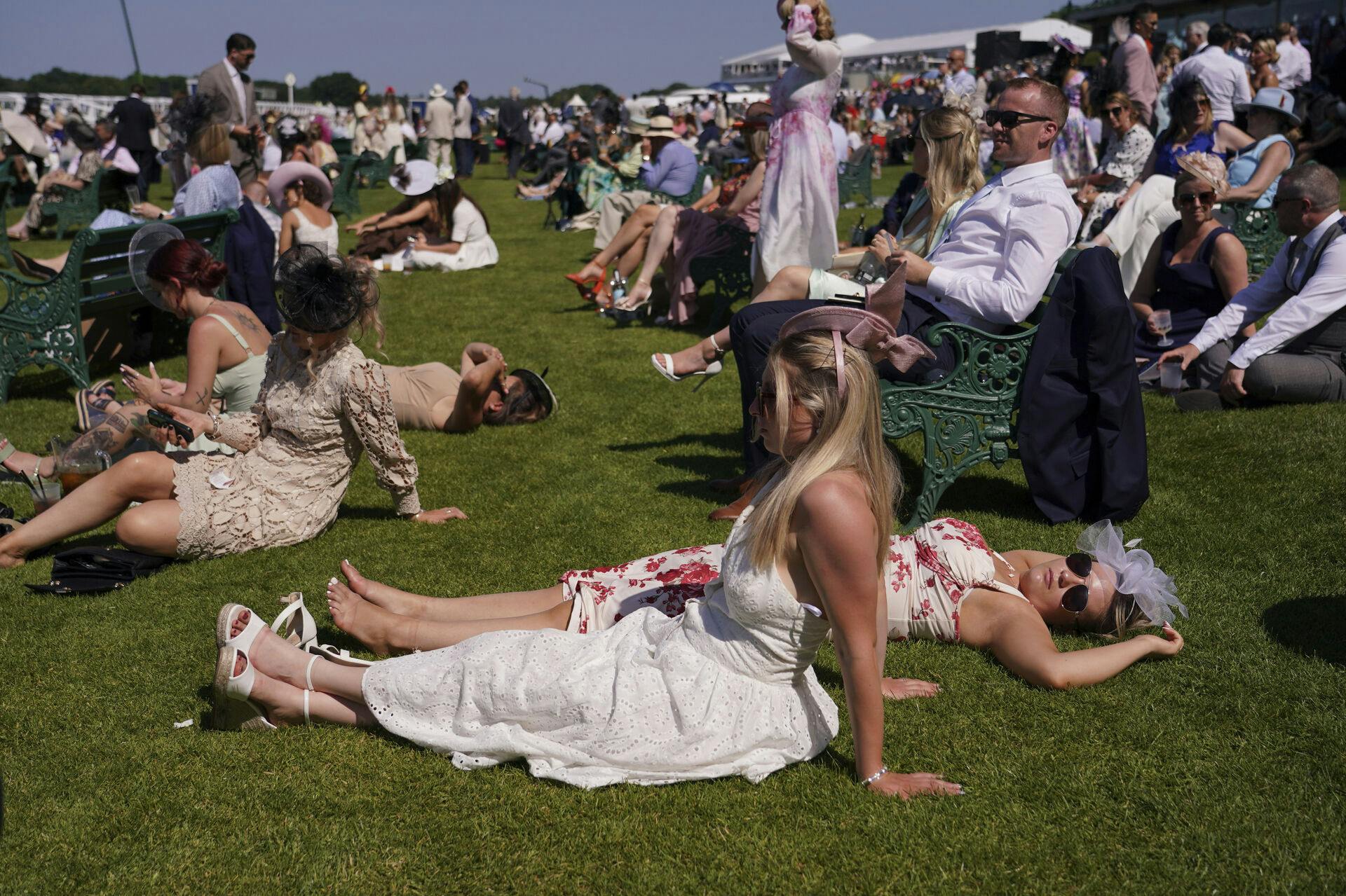 Væddeløbstilskuere strækker sig på græsset på andendagen for Royal Ascot, onsdag 18. juni. Samme dag måtte 42 modtage behandling mod hedeslag - én måtte på hospitalet.