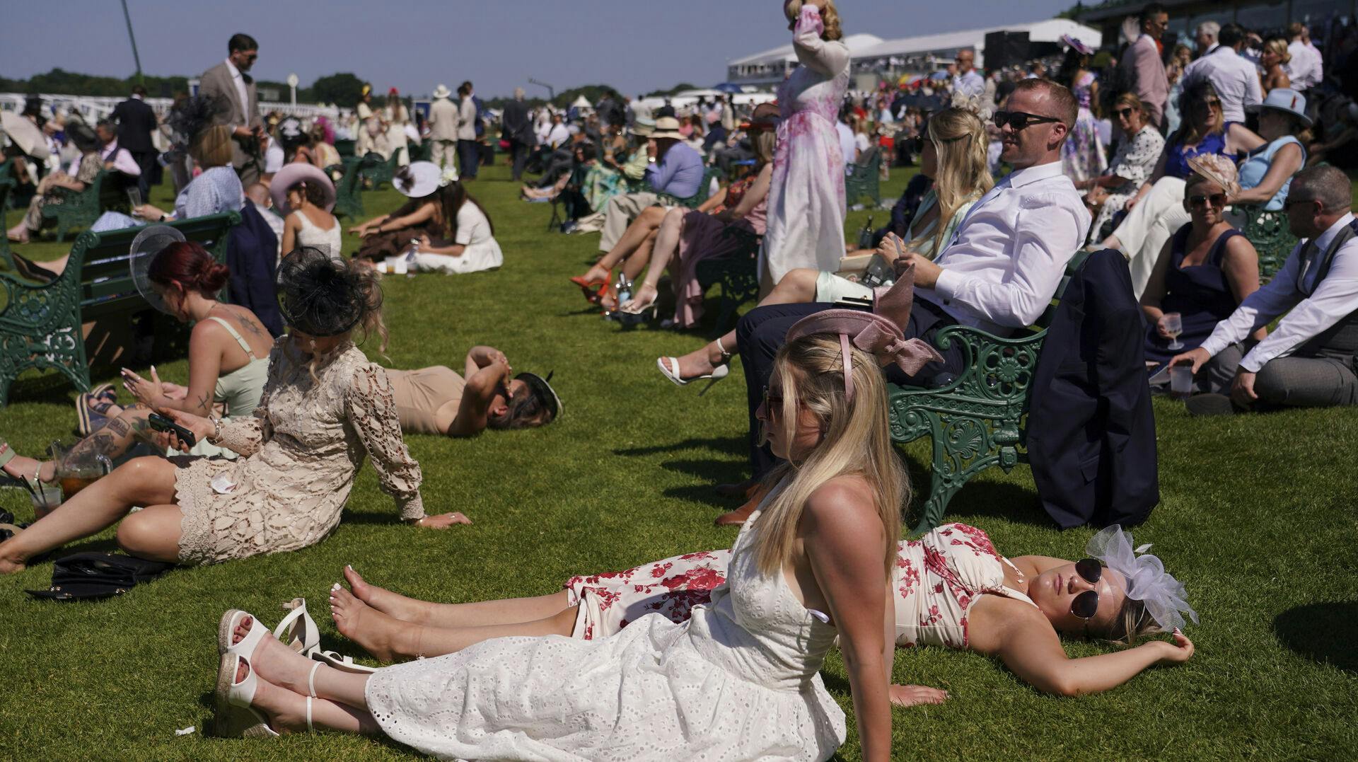 Væddeløbstilskuere strækker sig på græsset på andendagen for Royal Ascot, onsdag 18. juni. Samme dag måtte 42 modtage behandling mod hedeslag - én måtte på hospitalet.
