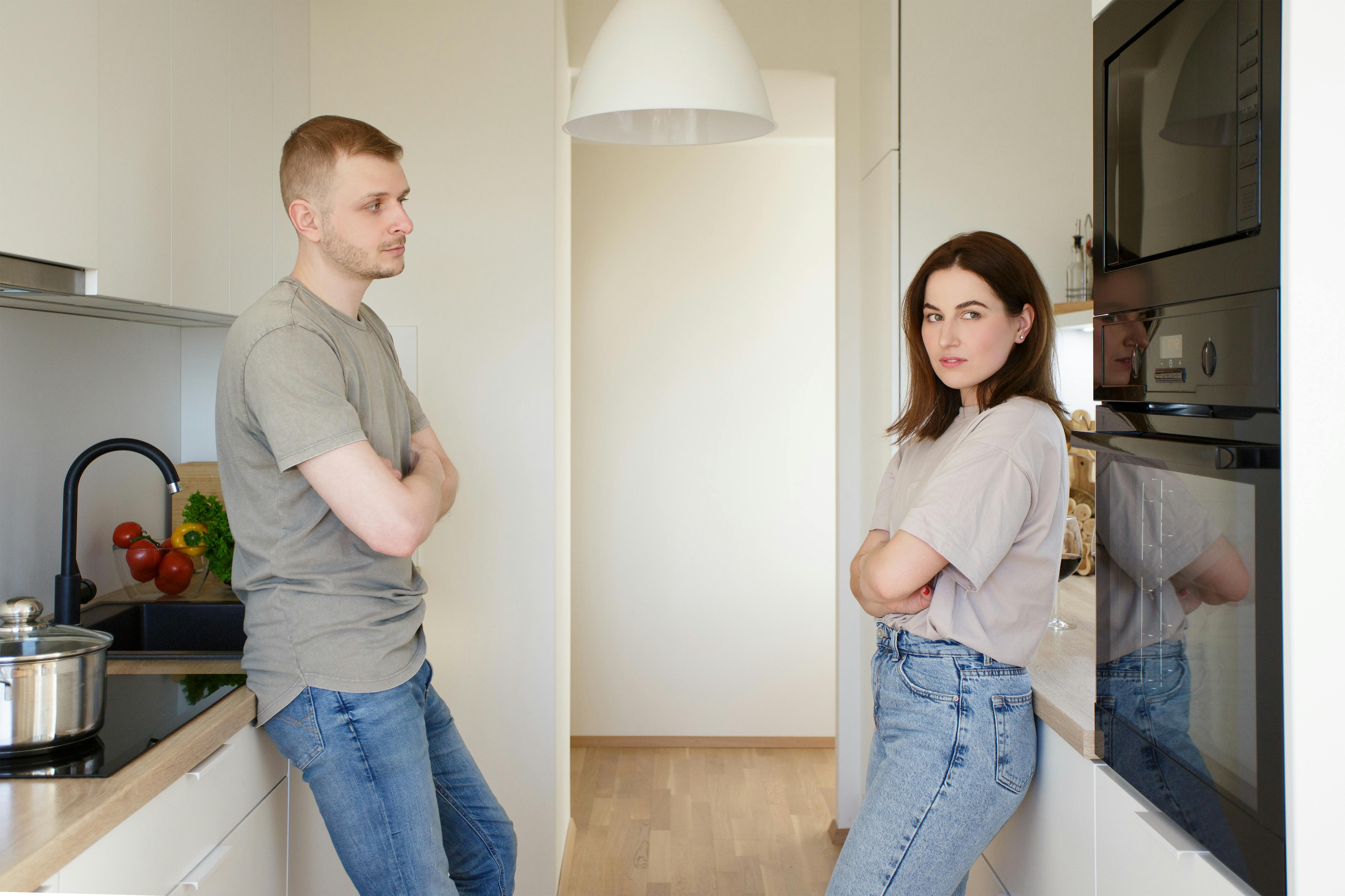 family, relationship and quarrel concept - sad couple standing in the kitchen after quarrel