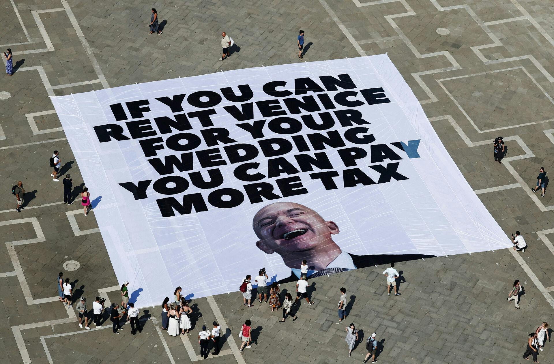 A large banner against Amazon founder Jeff Bezos lies on the ground, placed by Greenpeace Italy activists and UK activist group Everyone Hates Elon, in St. Mark's Square, ahead of the expected wedding of Bezos and Lauren Sanchez, in Venice, Italy, June 23, 2025. REUTERS/Yara Nardi