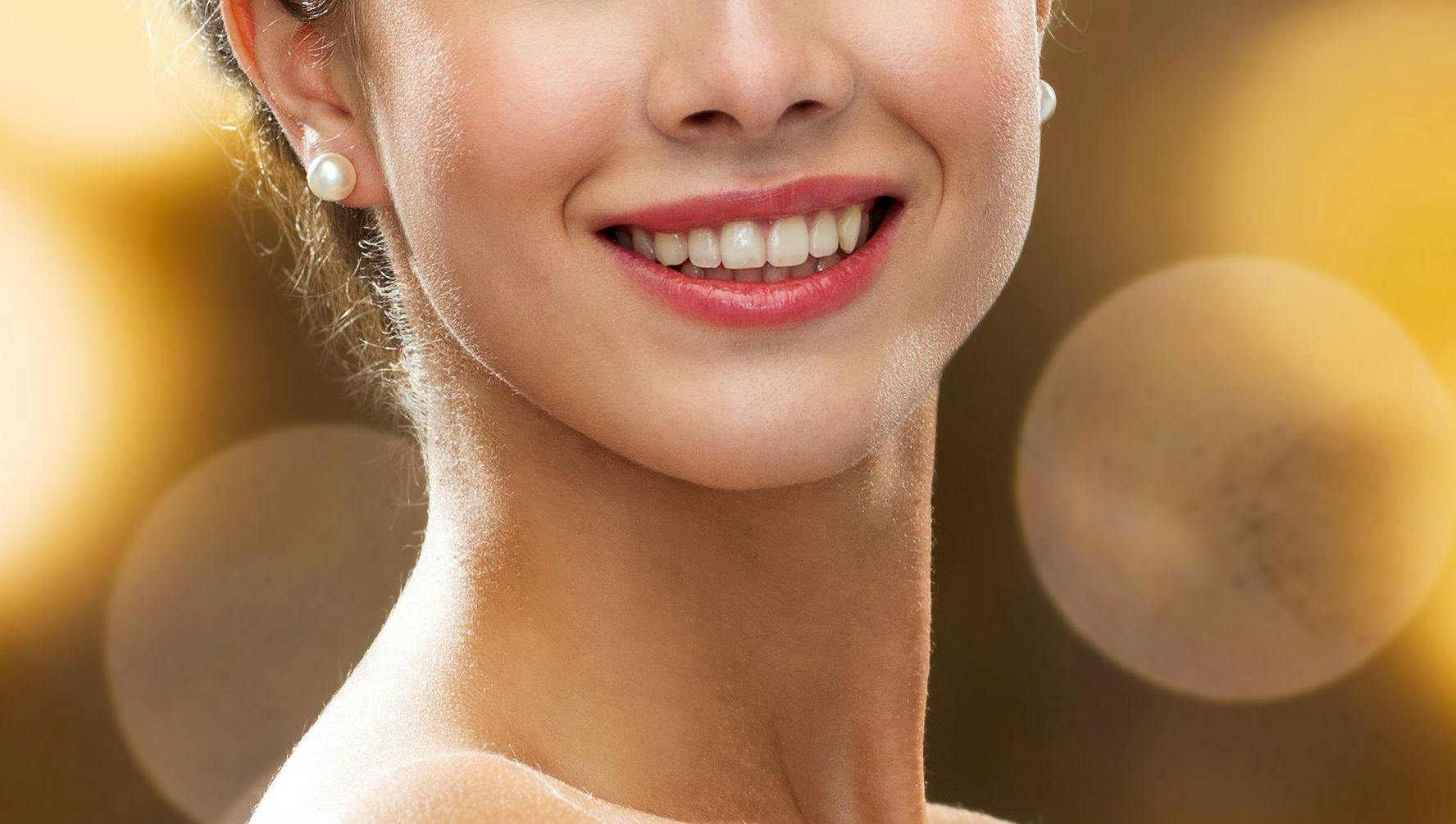 people, holidays, jewelry and luxury concept - smiling woman in evening dress and pearl earring over lights background