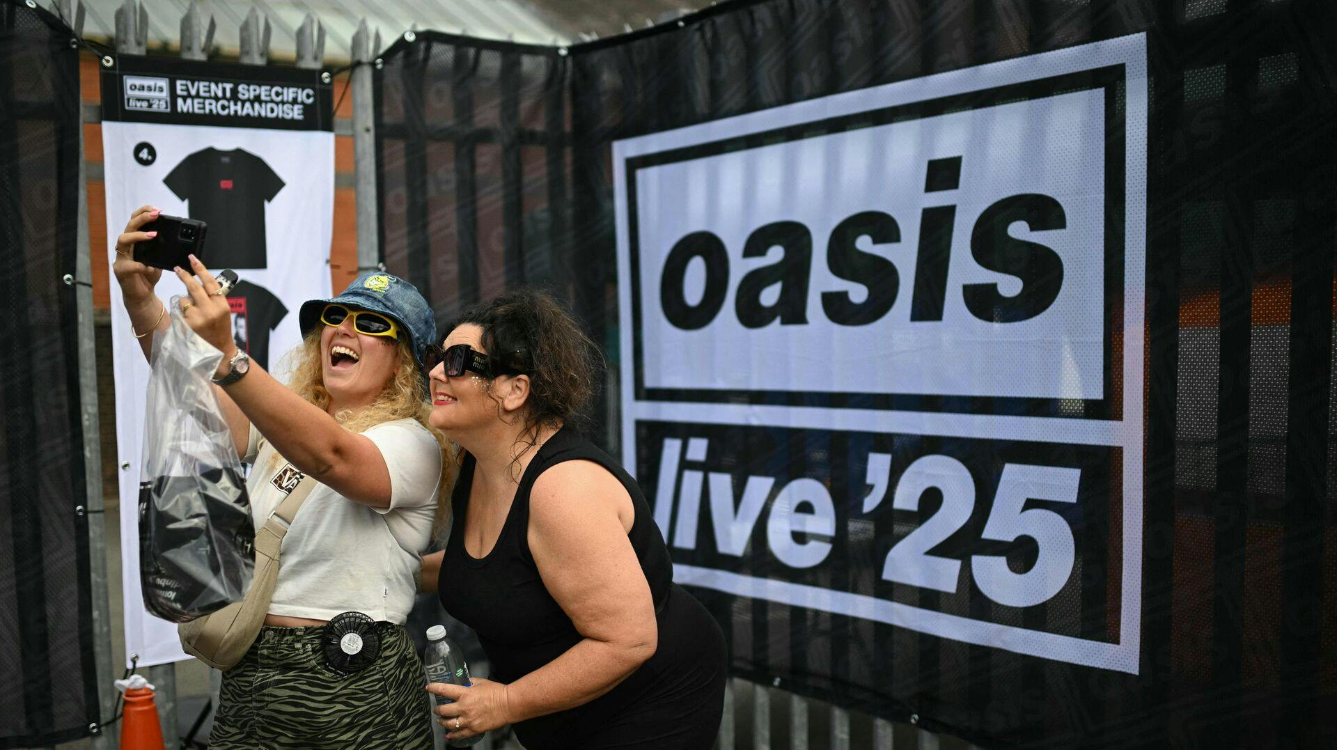 Fans af det britiske rockband Oasis tager en selfie, da de ankommer til Principality Stadium i Cardiff den 4. juli 2025 for at deltage i åbningskoncerten på deres længe ventede genforeningsturné.