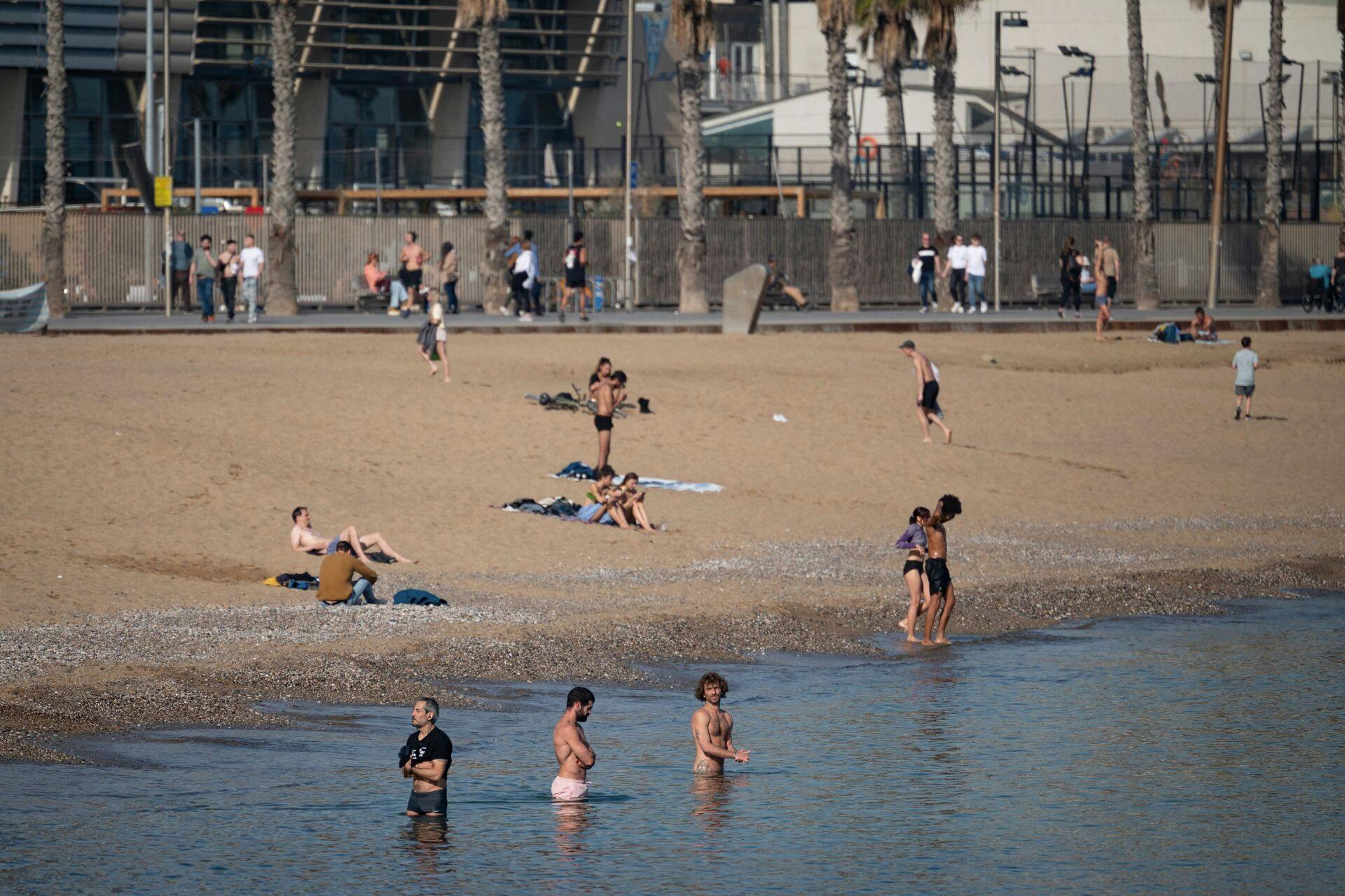 People sunbathe and cool off in the sea on the San Sebastian beach in Barcelona on January 26, 2024 as temperatures around 30°C were recorded in Spain. Spain is affected by a heat wave worthy of the start of summer in the middle of January, according to the meteorological agency (Aemet), which is worried about this "anomaly" . (Photo by Josep LAGO / AFP)