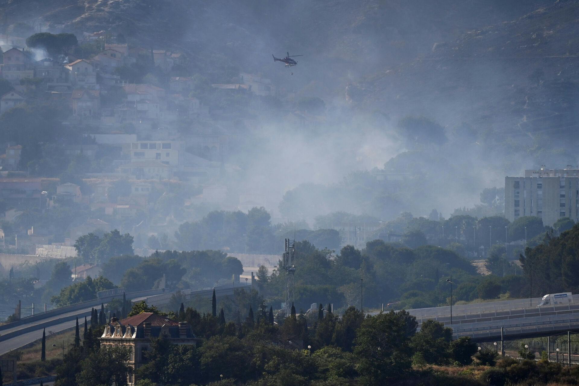 A helicopter flies over smoke rising from a fast-moving wildfire spreading on the outskirts of Marseille, southern France, July 8, 2025. REUTERS/Alexandre Dimou TPX IMAGES OF THE DAY