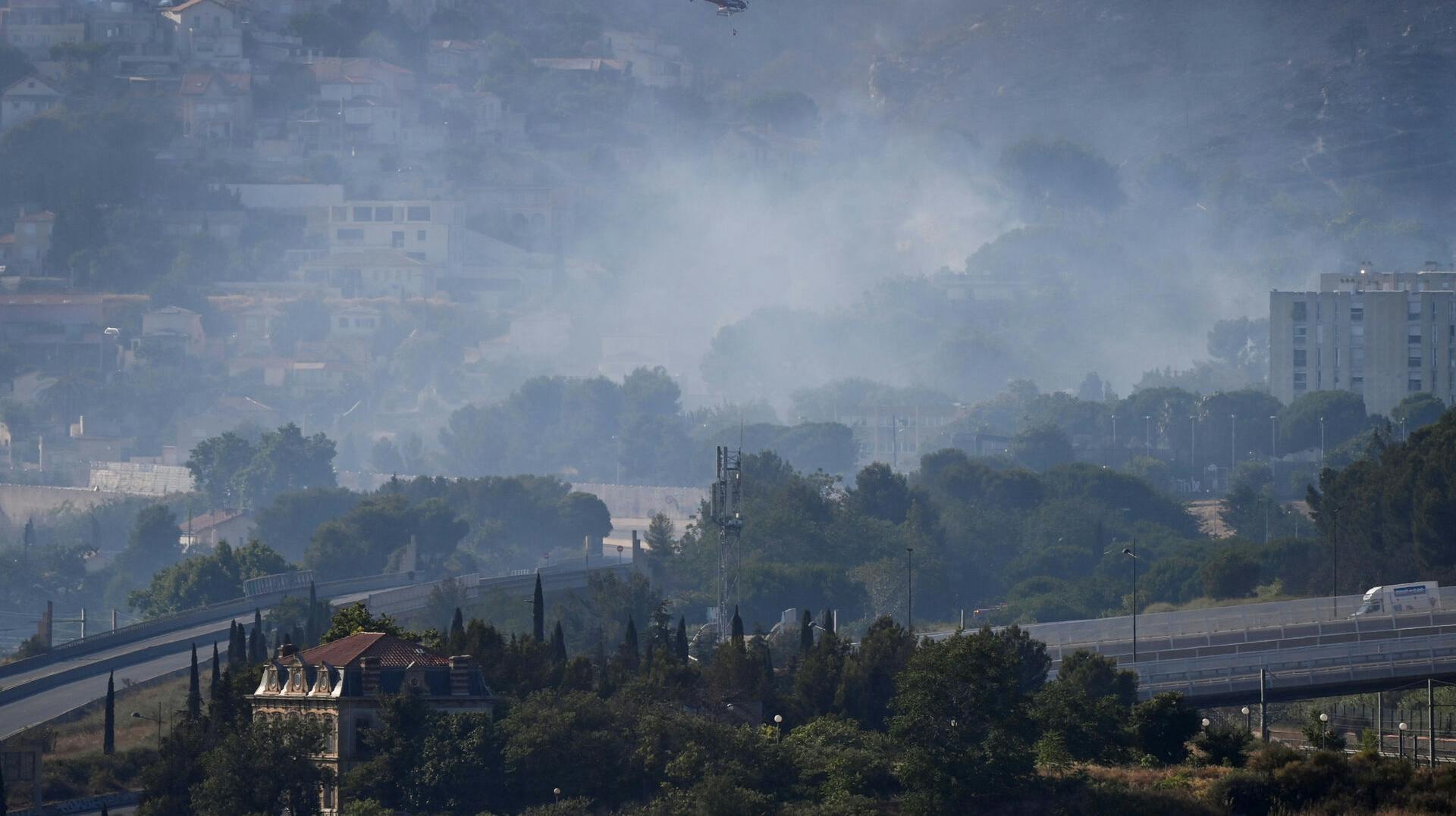 A helicopter flies over smoke rising from a fast-moving wildfire spreading on the outskirts of Marseille, southern France, July 8, 2025. REUTERS/Alexandre Dimou TPX IMAGES OF THE DAY