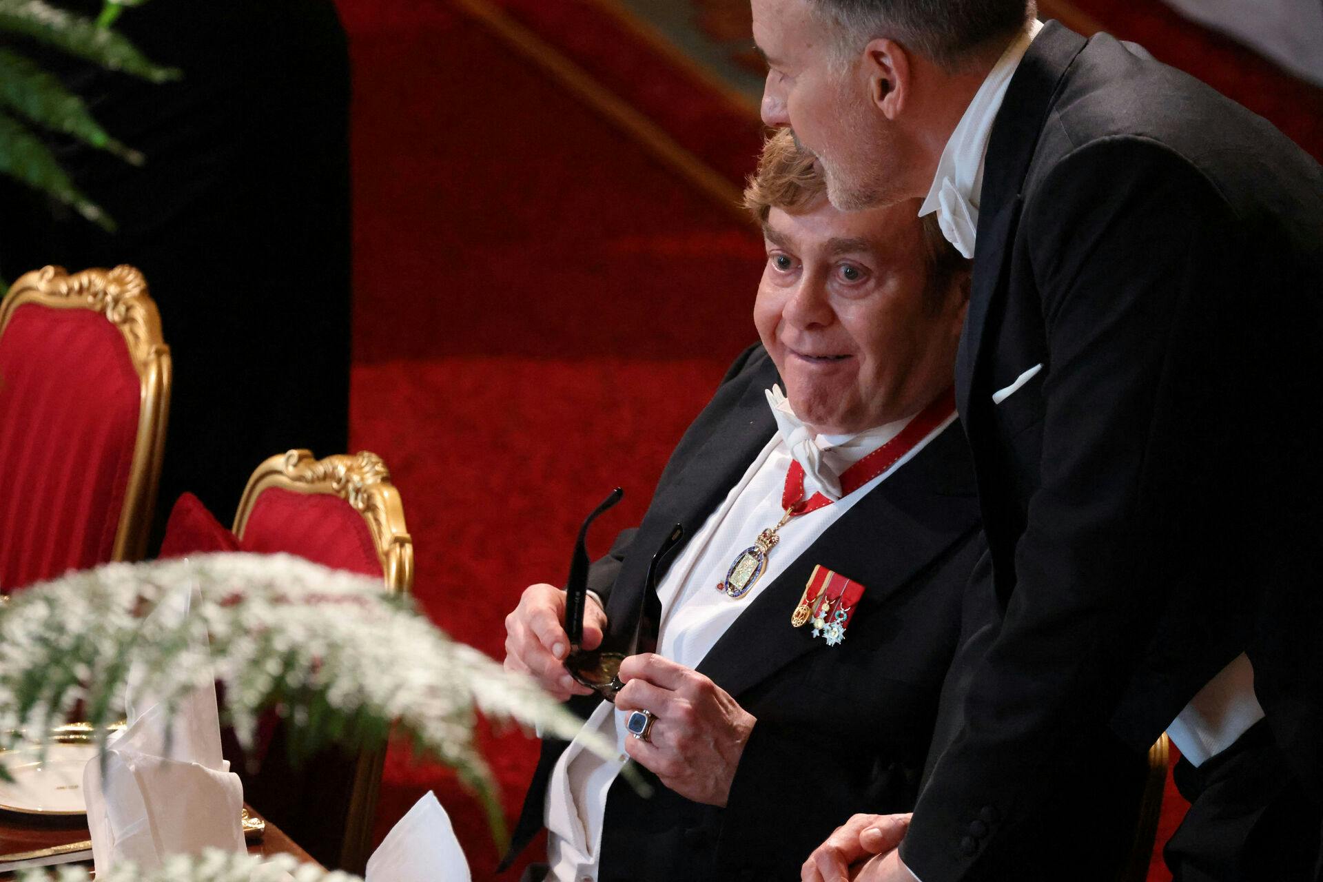 Elton John og David Furnish blev mod den normale etikette sat ved siden af hinanden, så David kunne støtte sin næsten blinde mand