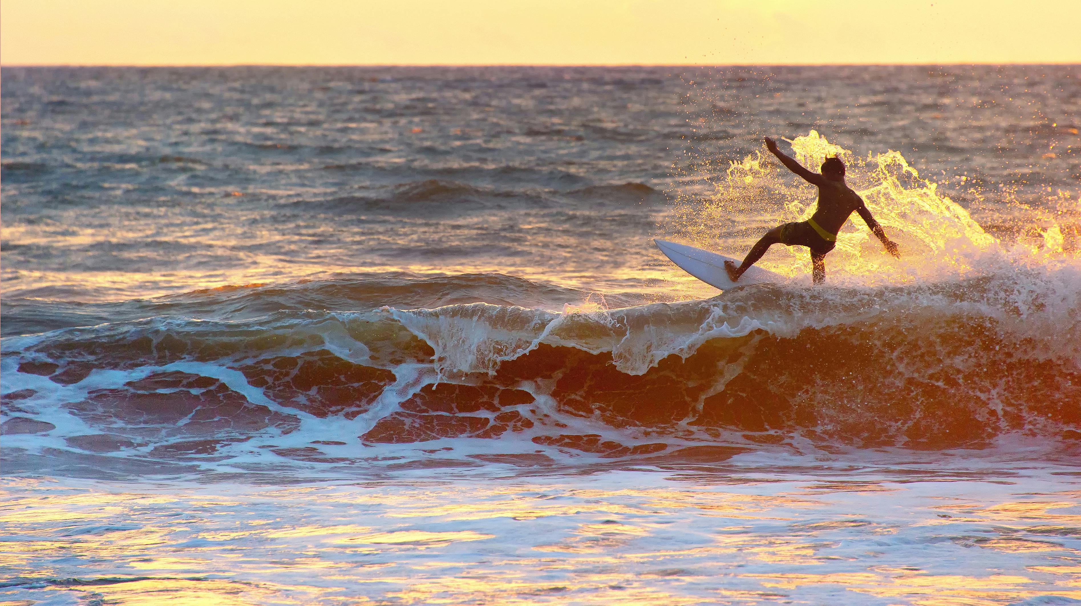 Surfer surf in the ocean at sunset. Bali island