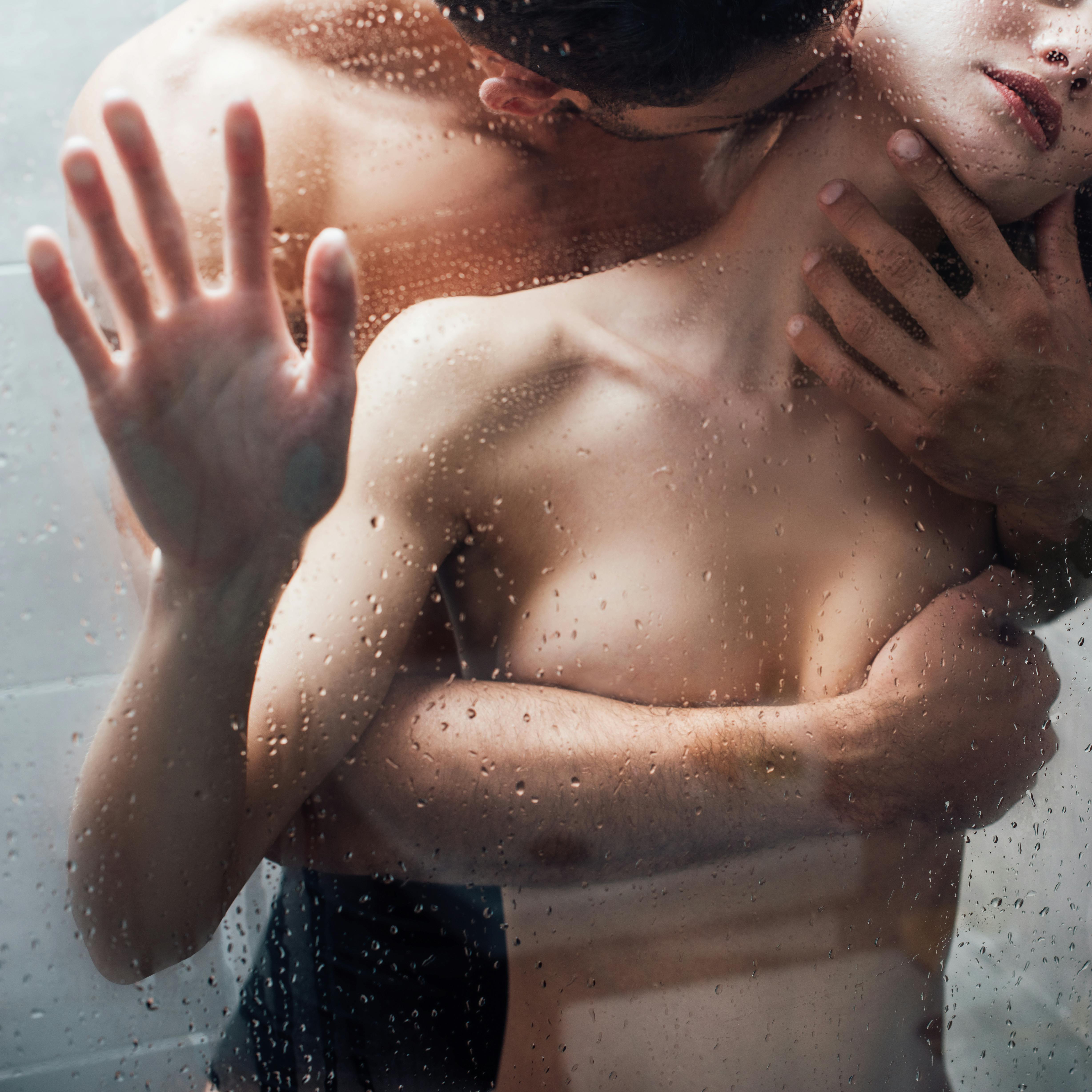 naked man passionately embracing and kissing woman in shower