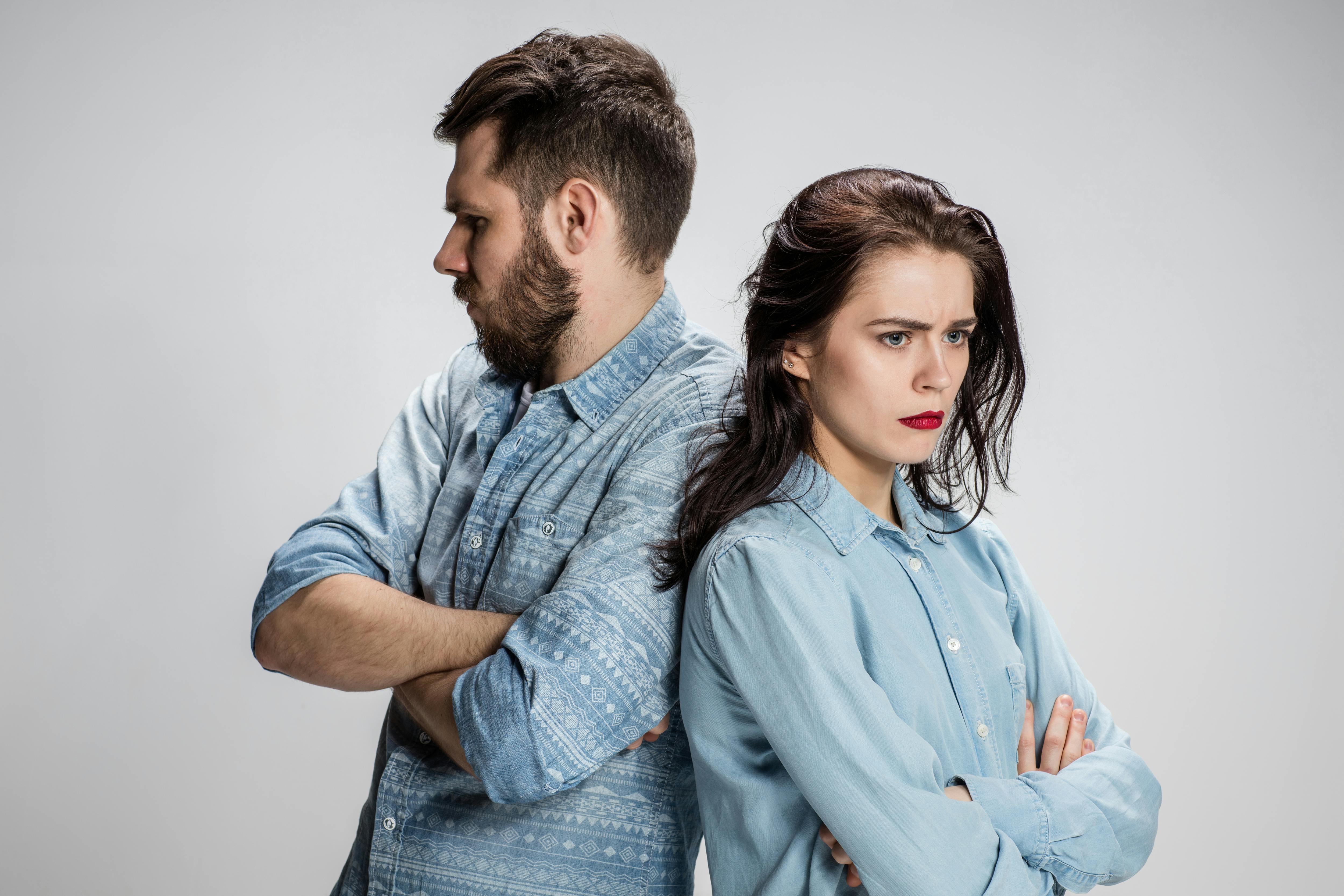 The young couple with different emotions during conflict on gray background