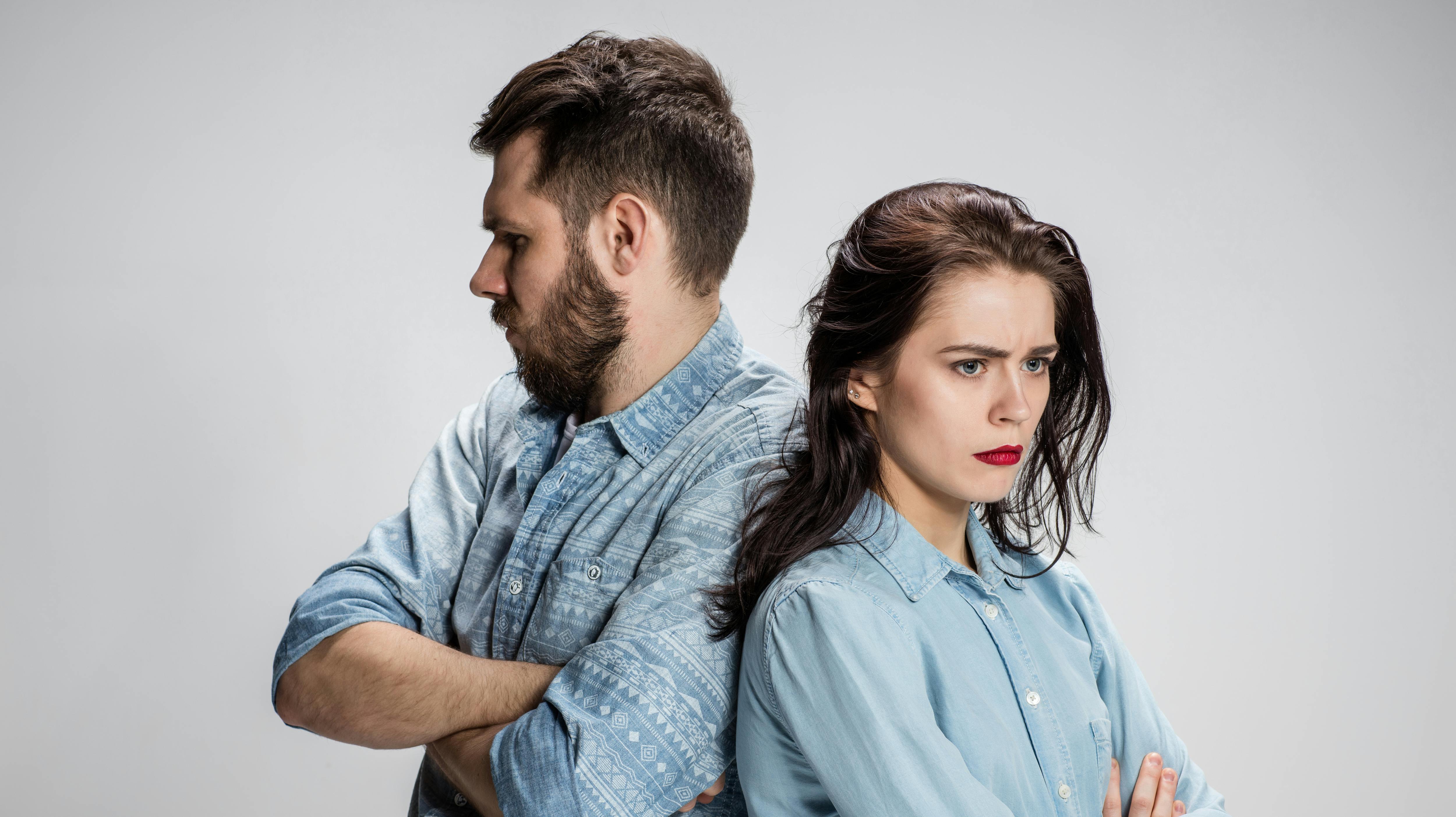 The young couple with different emotions during conflict on gray background