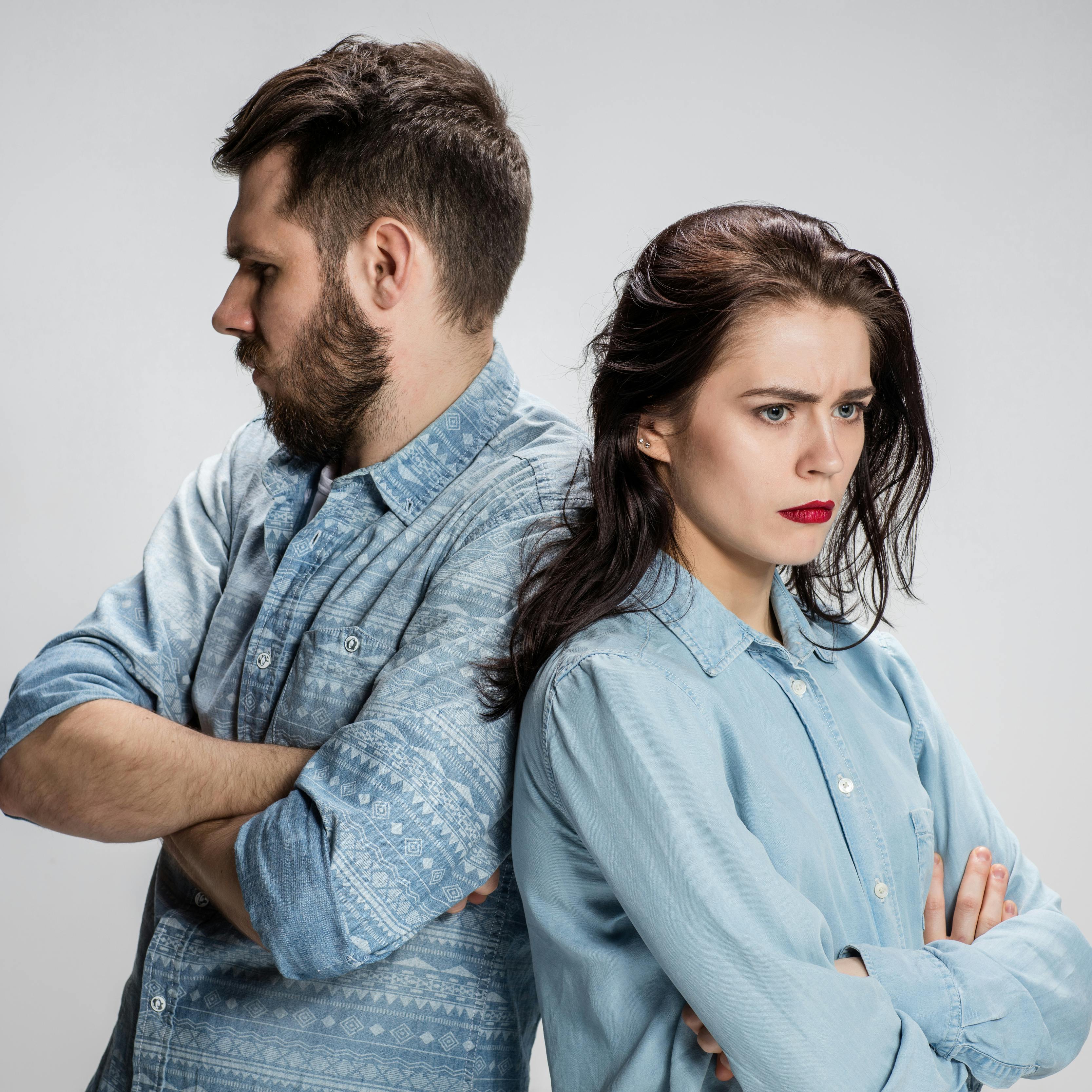 The young couple with different emotions during conflict on gray background