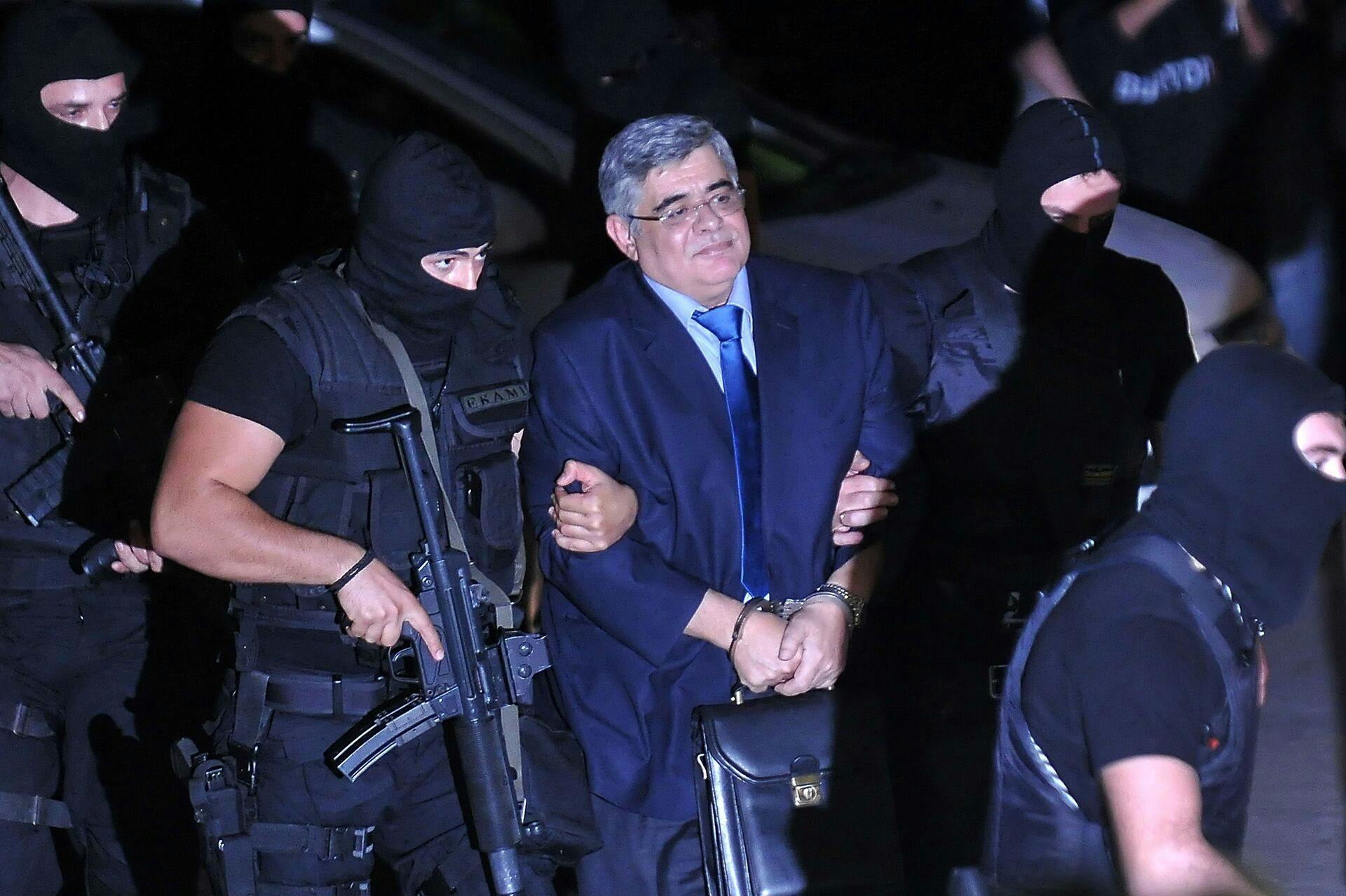 Det så voldsomt ud, da nynazisten Nikos Michaloliakos blev fragtet til retten i Athen af maskerede politibetjente.
