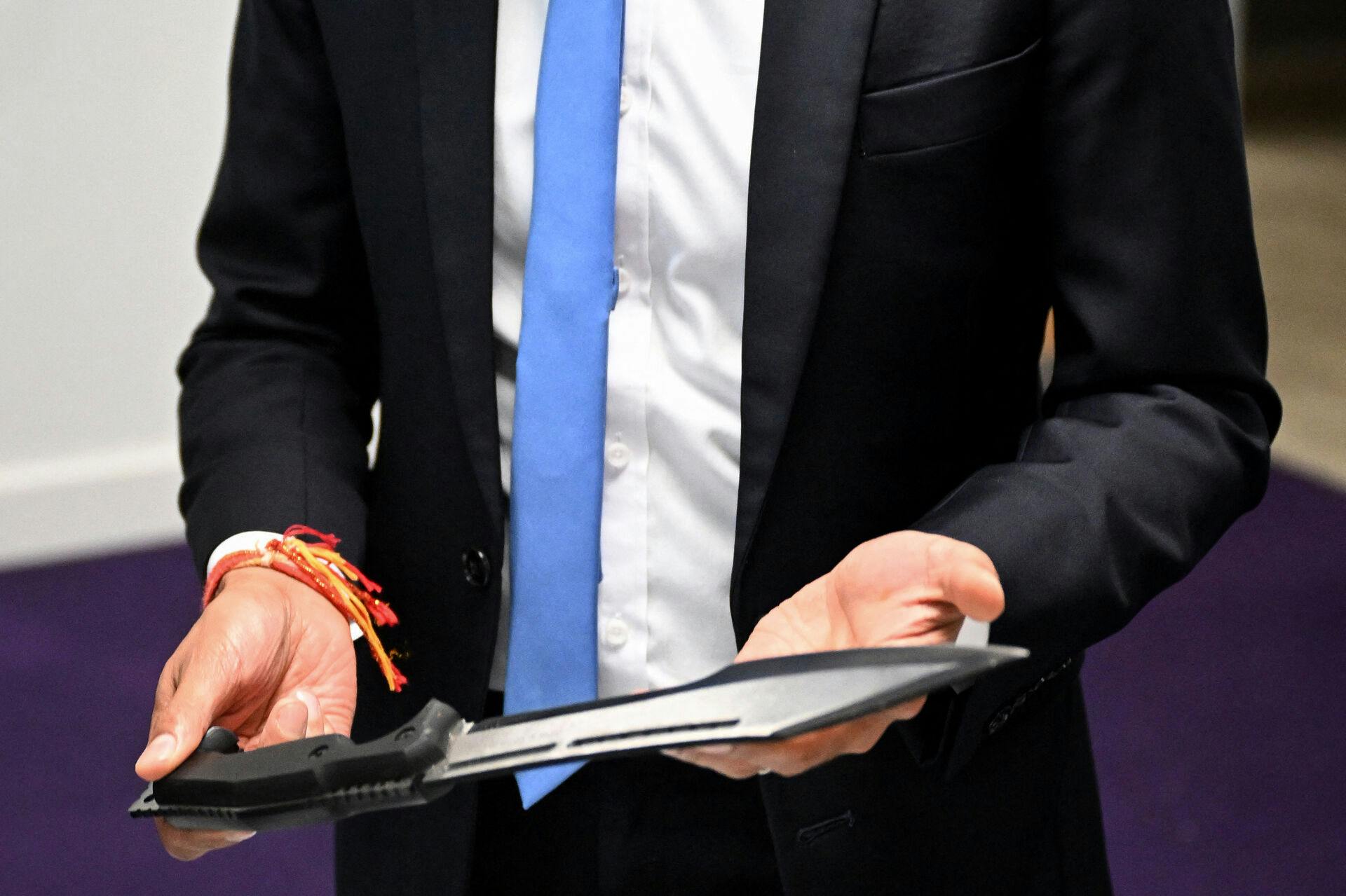 Britain's Prime Minister Rishi Sunak holds a machete seized from knife attacks during a visit to the Kilburn police station, northwest of London, on August 30, 2023. JUSTIN TALLIS / POOL / AFP