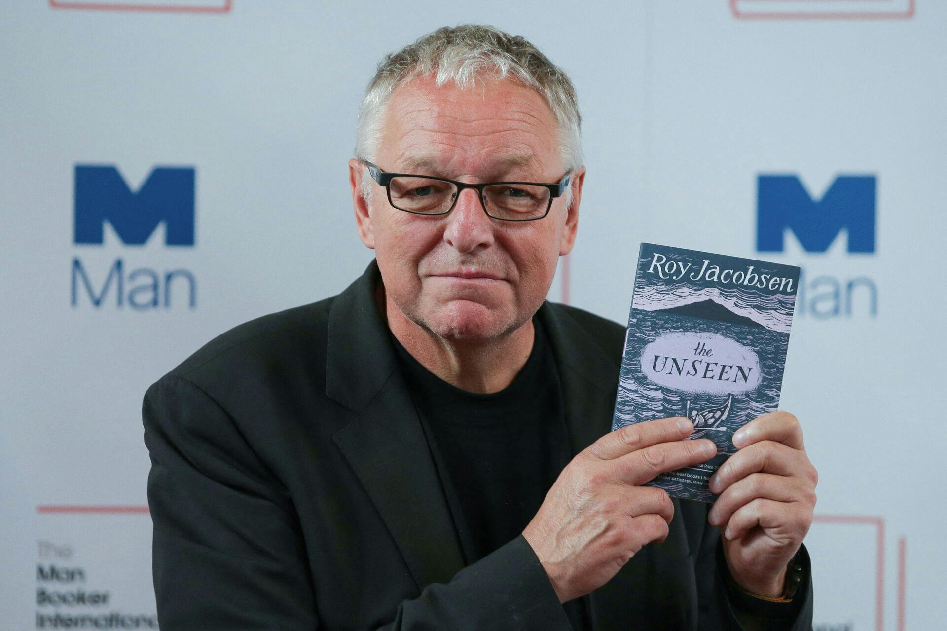 Norwegian author Roy Jacobsen poses for a photograph with his book 'The Unseen', at the shortlist photocall for the Man Booker International Prize at St James' Church in London on June 13, 2017.  Daniel LEAL / AFP