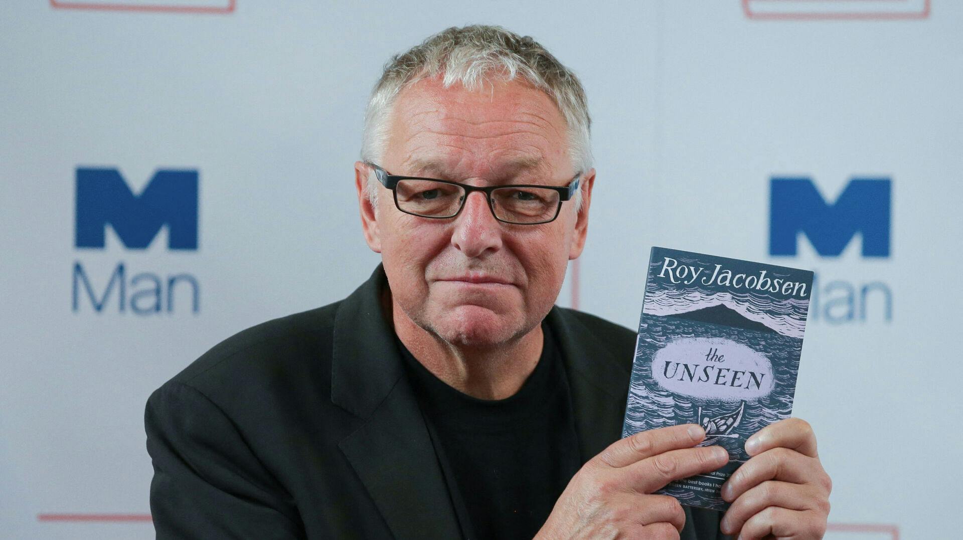 Norwegian author Roy Jacobsen poses for a photograph with his book 'The Unseen', at the shortlist photocall for the Man Booker International Prize at St James' Church in London on June 13, 2017. Daniel LEAL / AFP
