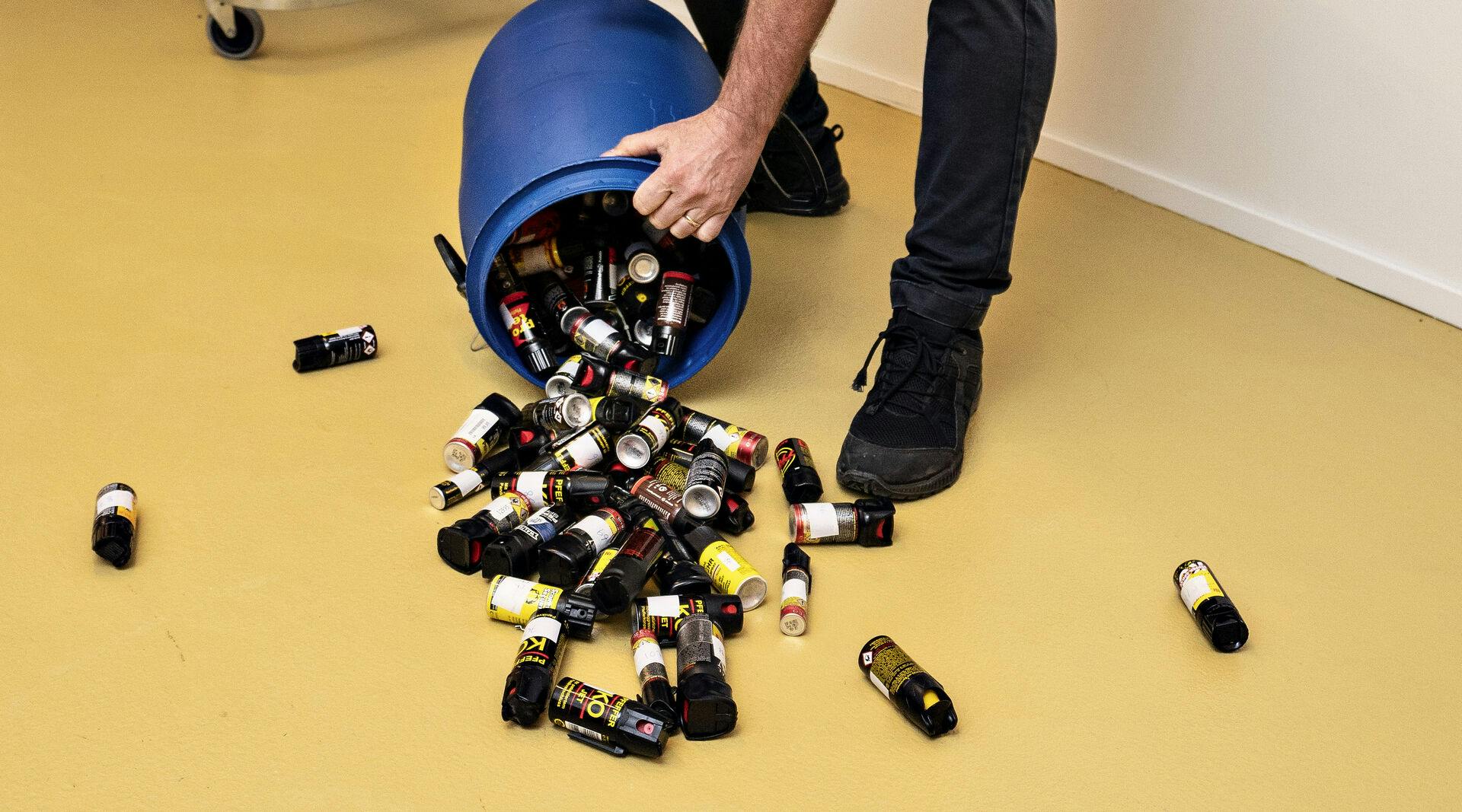 En betjent fremviser de mange pebersprays, der blev afleveret af borgere til politiet i forbindelse med ulovliggørelsen i 2019. Det er uvist, hvordan stjernemusikeren forholder sig til anklagen om at ville indføre hele 12 af de ulovlige våben.