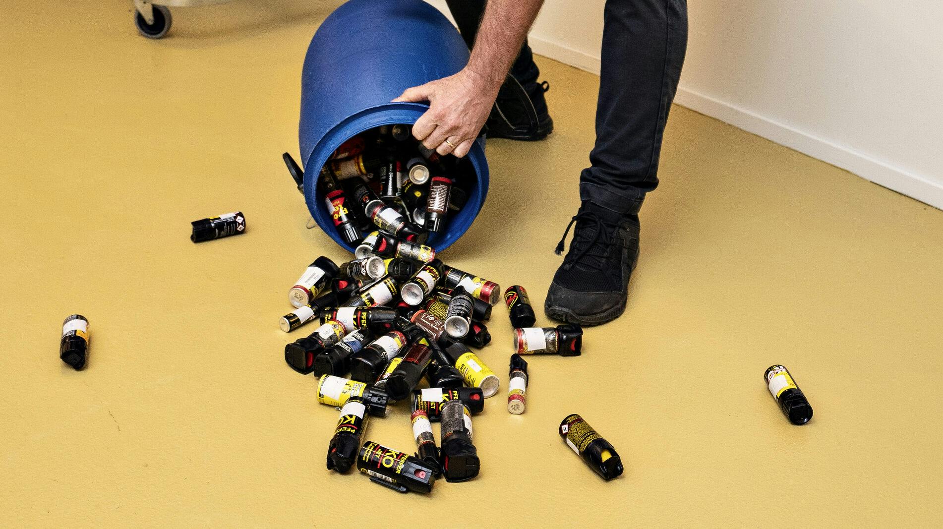 En betjent fremviser de mange pebersprays, der blev afleveret af borgere til politiet i forbindelse med ulovliggørelsen i 2019. Det er uvist, hvordan stjernemusikeren forholder sig til anklagen om at ville indføre hele 12 af de ulovlige våben.