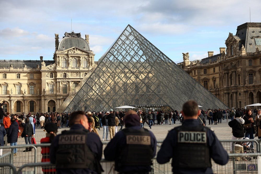 Police officers stand guard near the Louvre Pyramid, after French police arrested suspects in the Louvre heist case, at the Louvre Museum in Paris, France, October 26, 2025. REUTERS/Abdul Saboor - Foto: Abdul Saboor/Reuters
