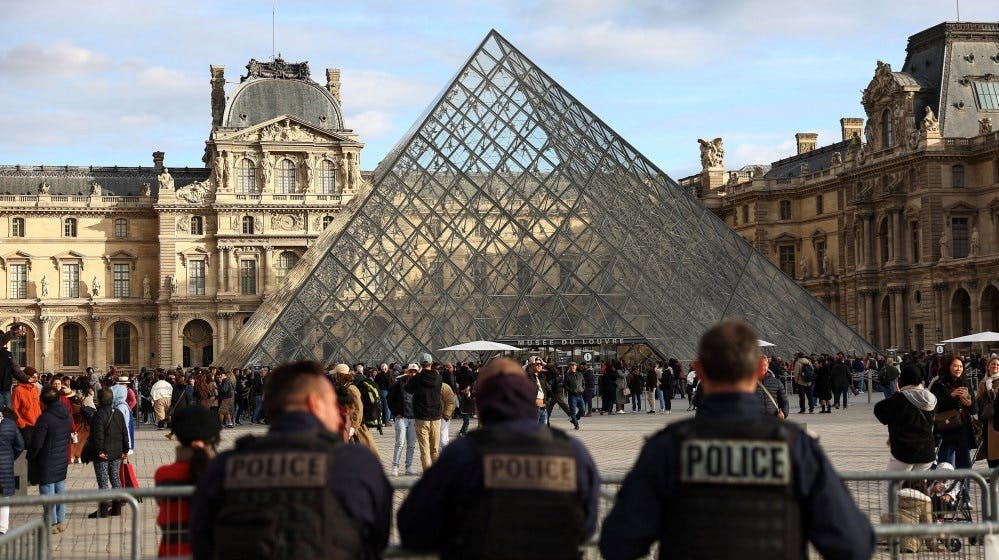 Police officers stand guard near the Louvre Pyramid, after French police arrested suspects in the Louvre heist case, at the Louvre Museum in Paris, France, October 26, 2025. REUTERS/Abdul Saboor - Foto: Abdul Saboor/Reuters