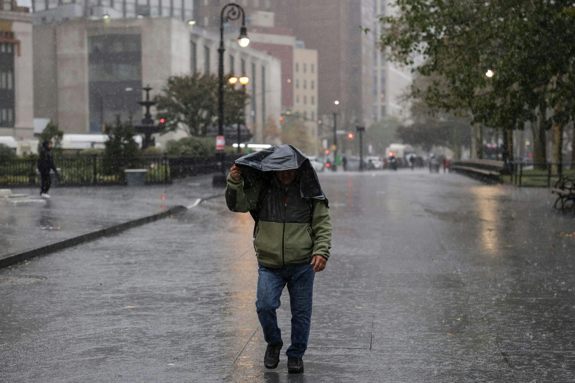 A person walks in the rain during heavy downpour on October 30, 2025 New York City. (Photo by ANGELA WEISS / AFP)