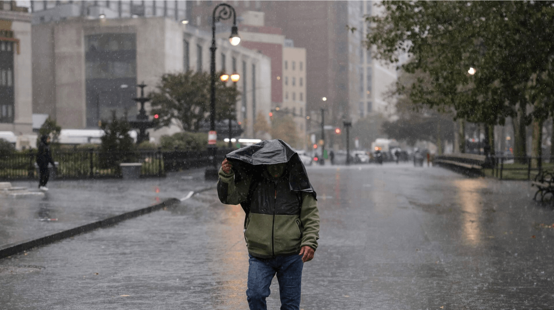A person walks in the rain during heavy downpour on October 30, 2025 New York City. (Photo by ANGELA WEISS / AFP)