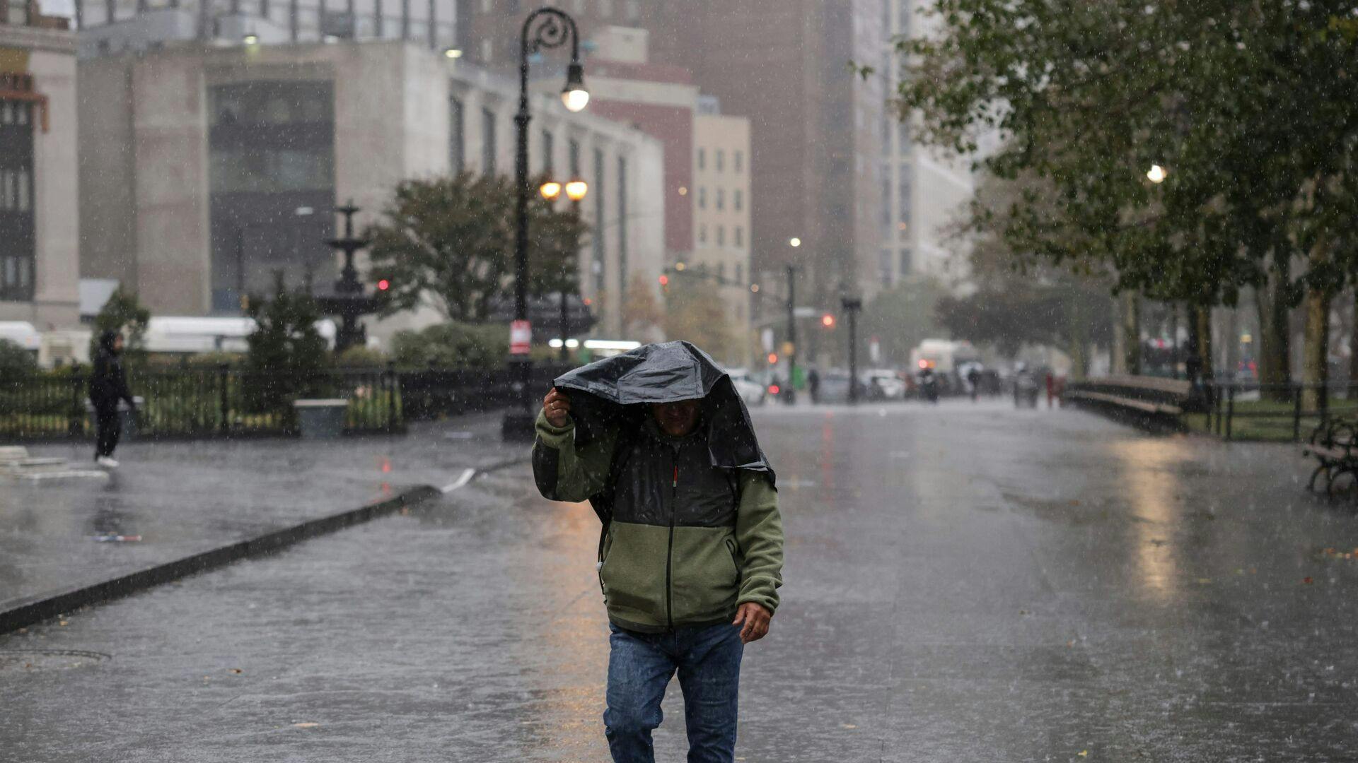 A person walks in the rain during heavy downpour on October 30, 2025 New York City. (Photo by ANGELA WEISS / AFP)