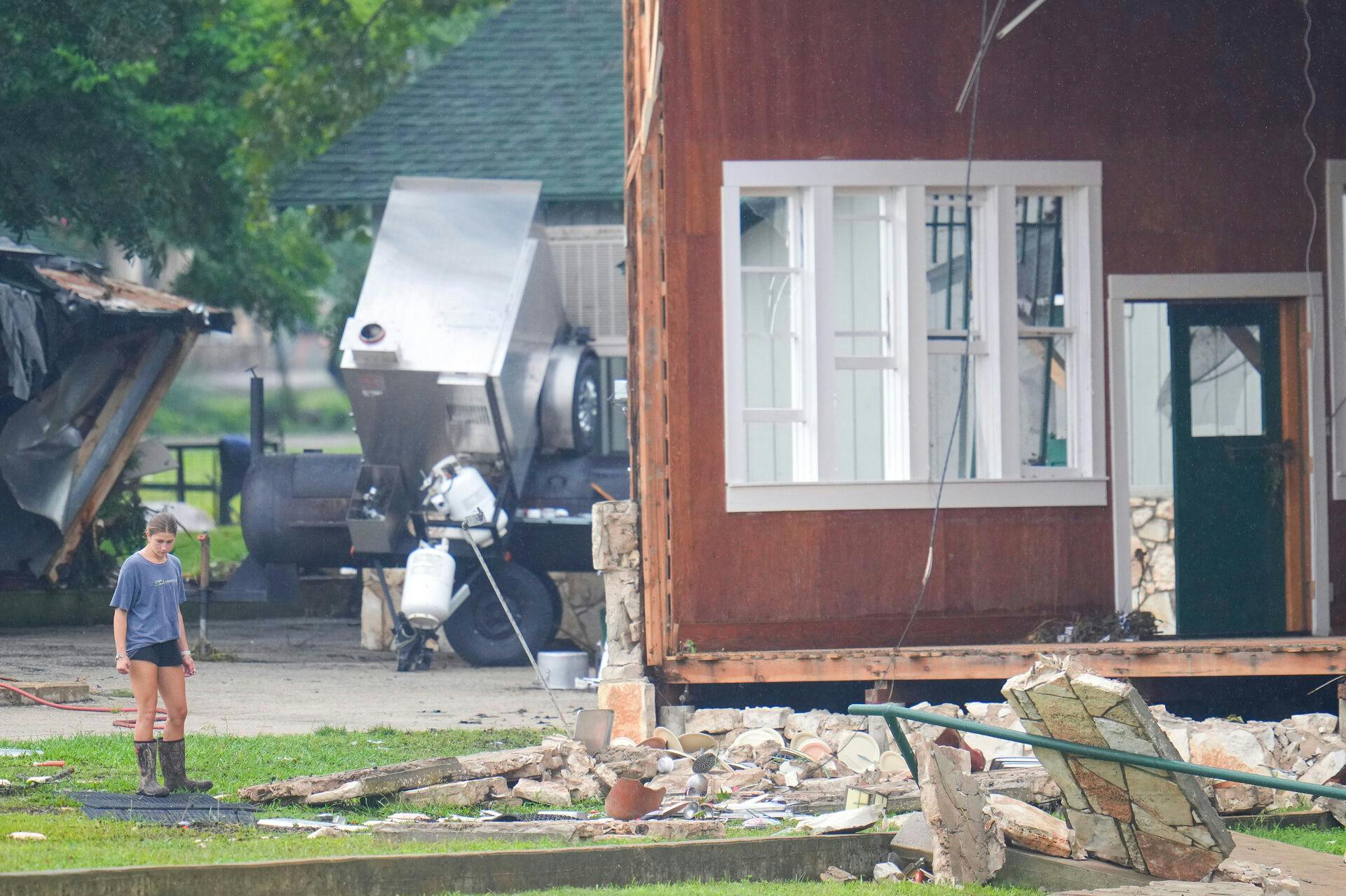 FILE - A person looks at damage to the main building at Camp Mystic along the banks of the Guadalupe River after a flash flood swept through the area, July 6, 2025, in Hunt, Texas. (AP Photo/Julio Cortez)