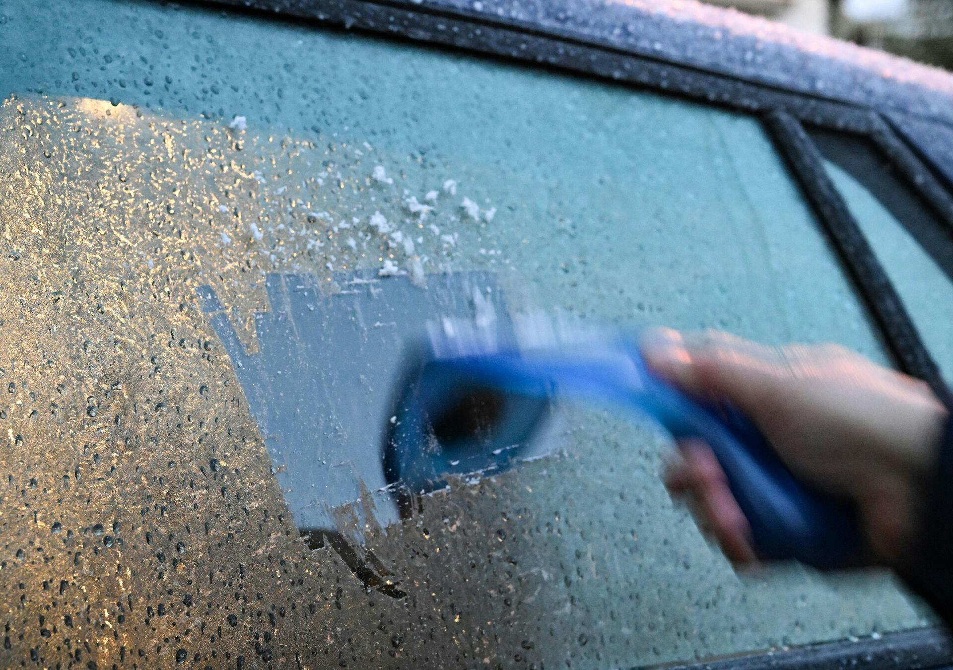18 November 2025, Baden-Württemberg, Stuttgart: A man scrapes a car windshield free of a layer of ice in the morning. The German Weather Service (DWD) is still expecting occasional fog and widespread icy conditions due to freezing rain on Tuesday morning. During the night it cooled down to minus 6 degrees. The mountains in particular will be affected by moderate frost. Photo by: Bernd Weißbrod/picture-alliance/dpa/AP Images