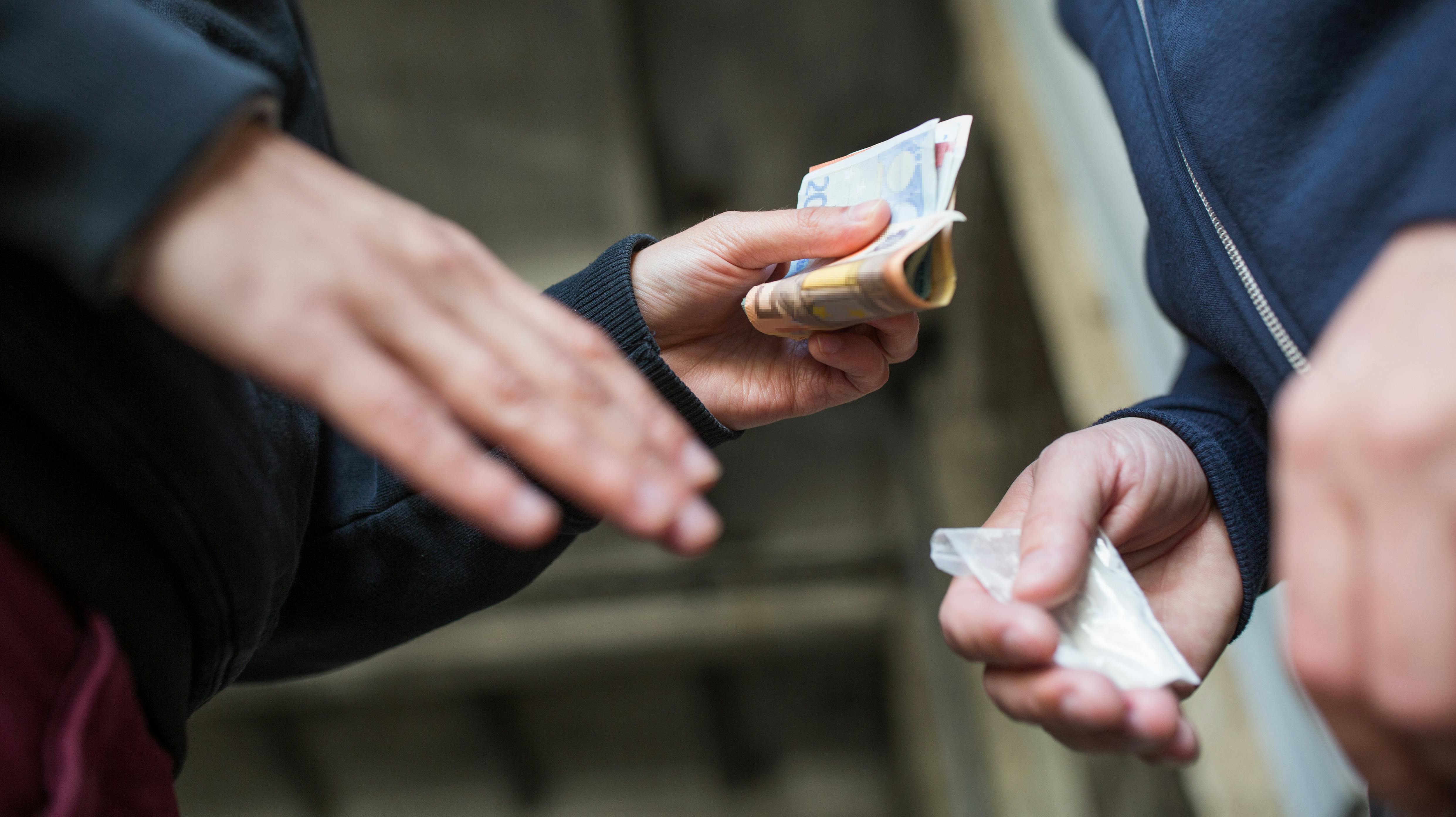 drug trafficking, crime, addiction and sale concept - close up of addict with money buying dose from dealer on street