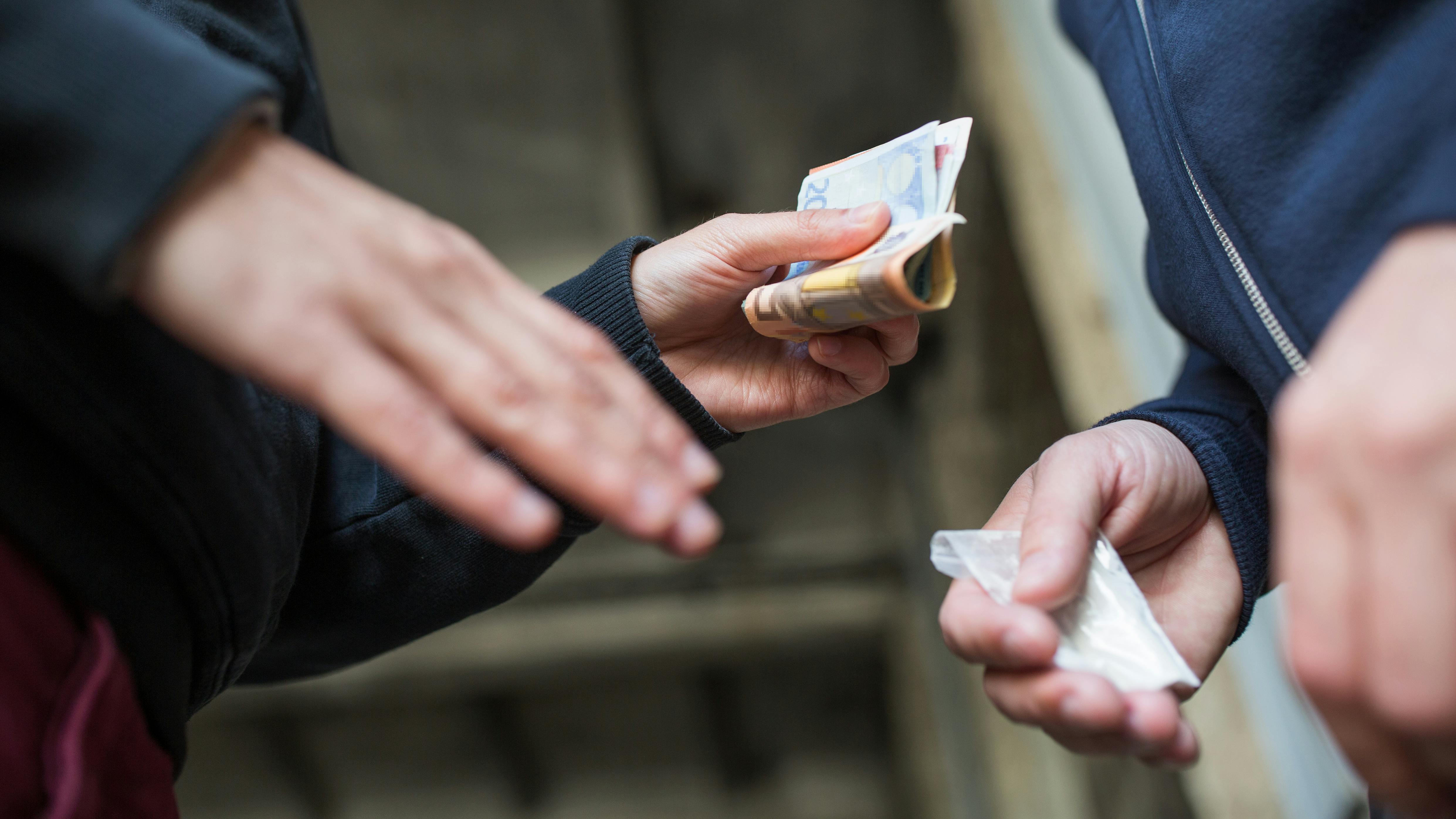 drug trafficking, crime, addiction and sale concept - close up of addict with money buying dose from dealer on street