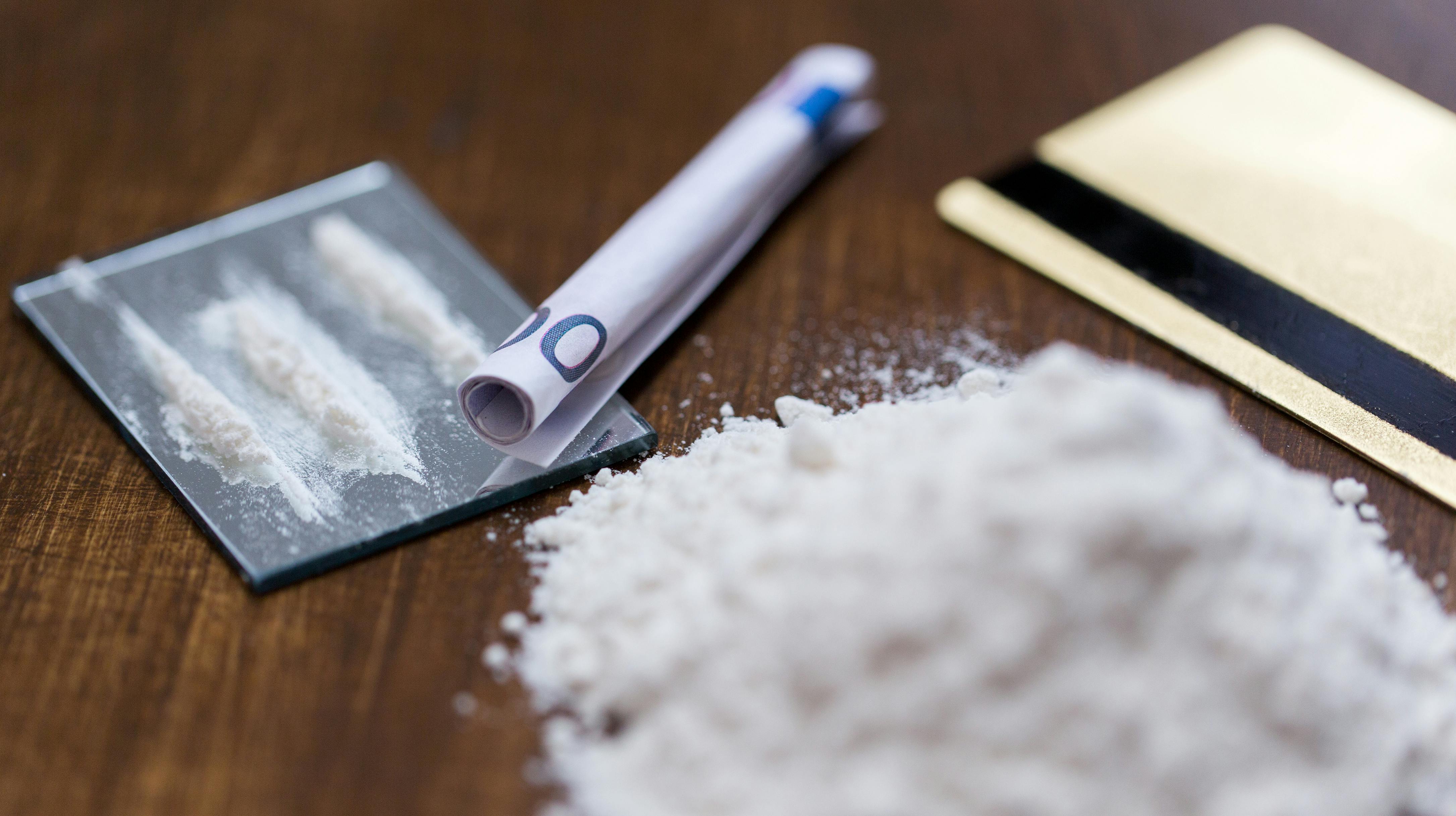 drug use, crime, addiction and substance abuse concept - close up of crack cocaine drug dose track on mirror with credit card and money