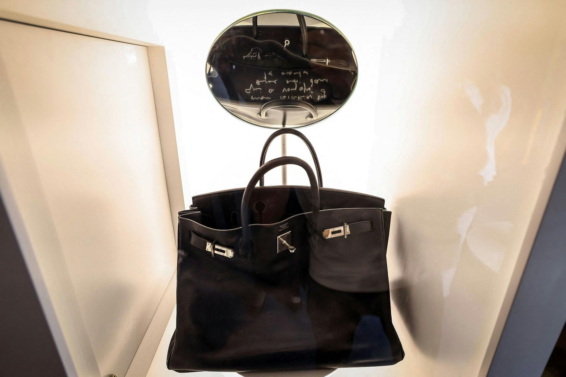 The Hermes Birkin Bag created for and named after British singer and actor Jane Birkin, and dubbed "Le Birkin Voyageur", is on display as part of the auction series during the Sotheby's "Abu Dhabi Collectors Week" in Abu Dhabi on December 2, 2025. The most personal of the actror's collection, it features her handwritten note (reflected in a displayed mirror), one of the five Birkins ever made for her by Hermes. (Photo by FADEL SENNA / AFP)
