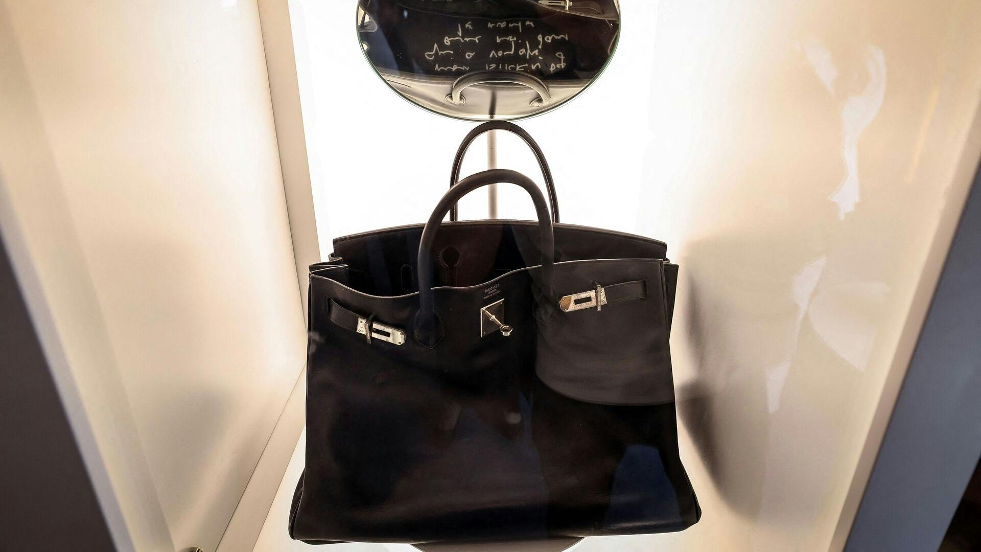 The Hermes Birkin Bag created for and named after British singer and actor Jane Birkin, and dubbed "Le Birkin Voyageur", is on display as part of the auction series during the Sotheby's "Abu Dhabi Collectors Week" in Abu Dhabi on December 2, 2025. The most personal of the actror's collection, it features her handwritten note (reflected in a displayed mirror), one of the five Birkins ever made for her by Hermes. (Photo by FADEL SENNA / AFP)