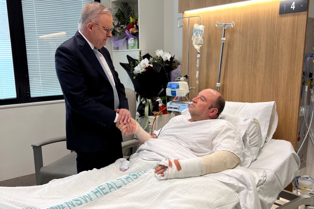 Premierminister trykker hånd med Bondi-helt i hospitalsseng.
