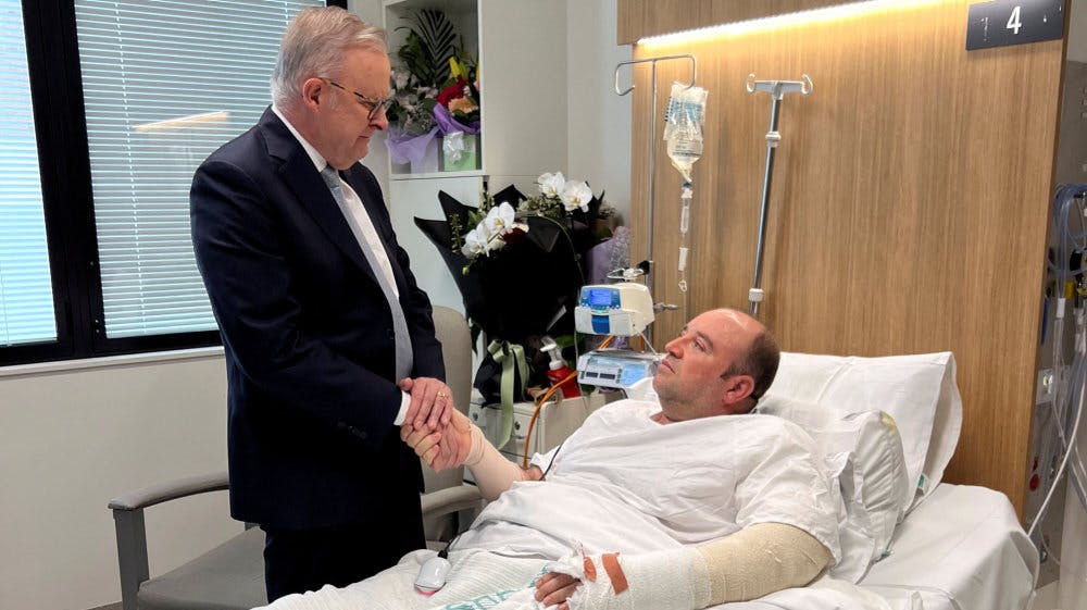 Premierminister trykker hånd med Bondi-helt i hospitalsseng.