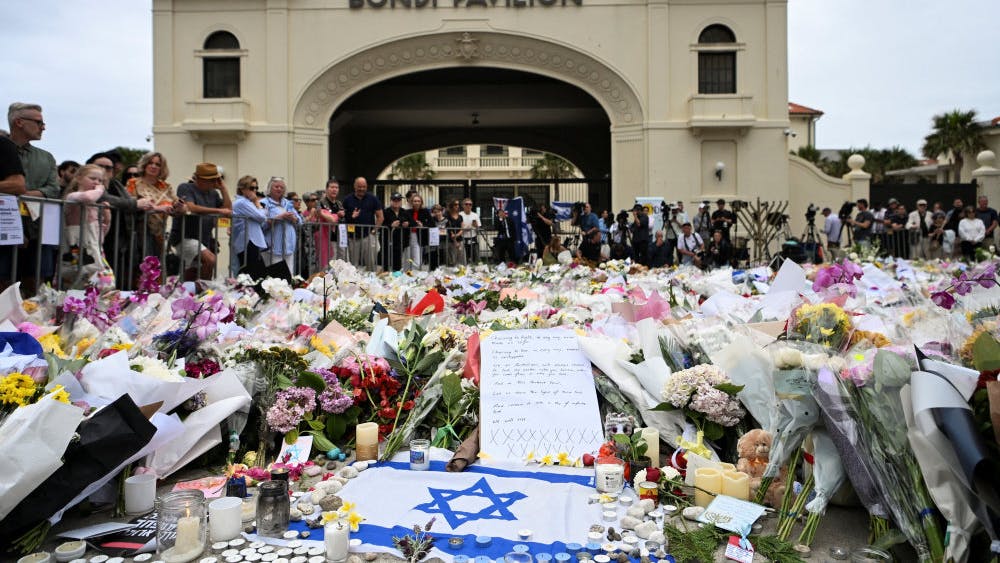 Et israelsk flag ligger foran bunker af blomster ved Bondi Beach. Søndag blev et jødisk Hanukkah-arrangement angrebet af to bevæbnede mænd.