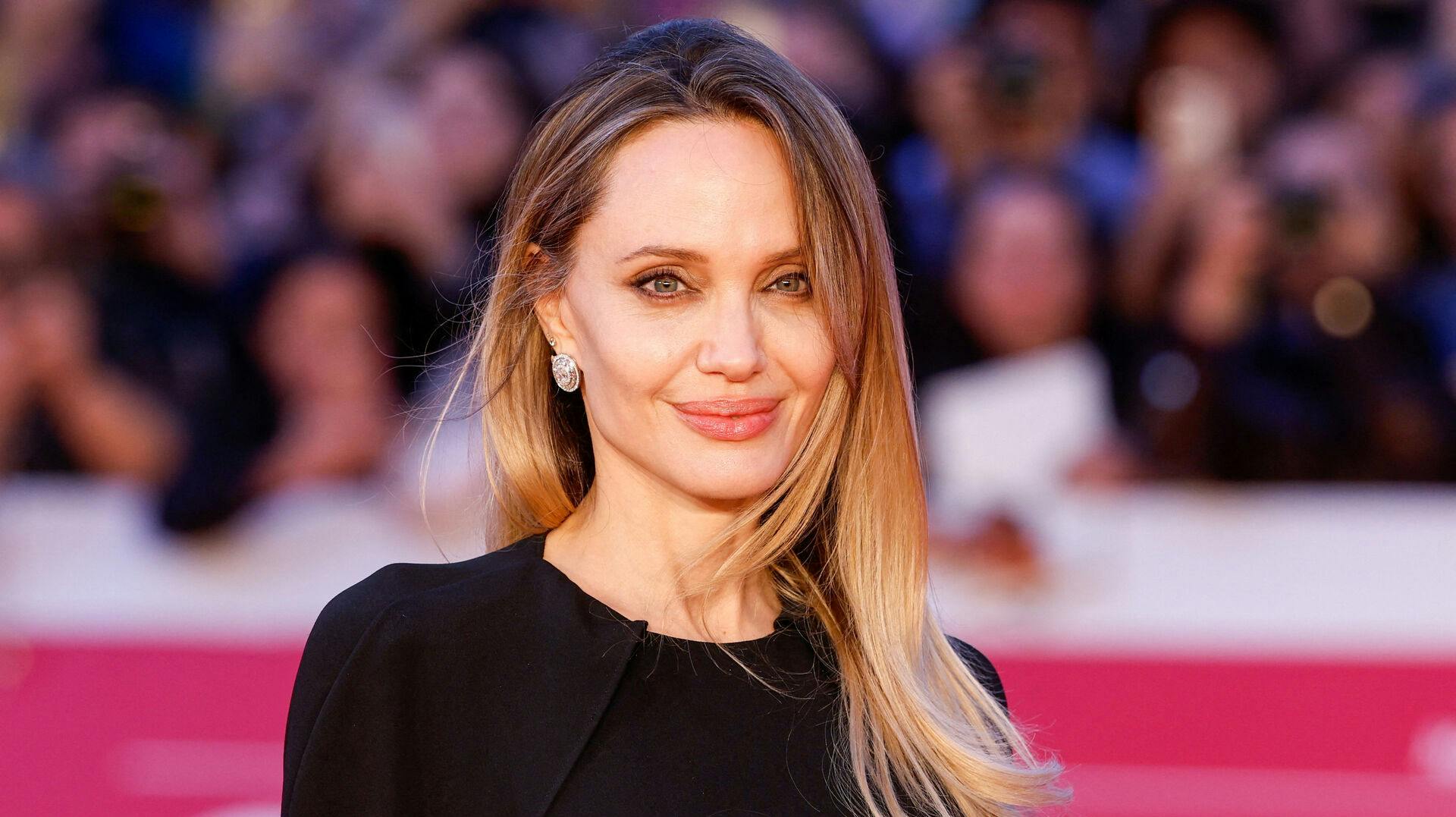 Cast member Angelina Jolie poses for pictures on red car