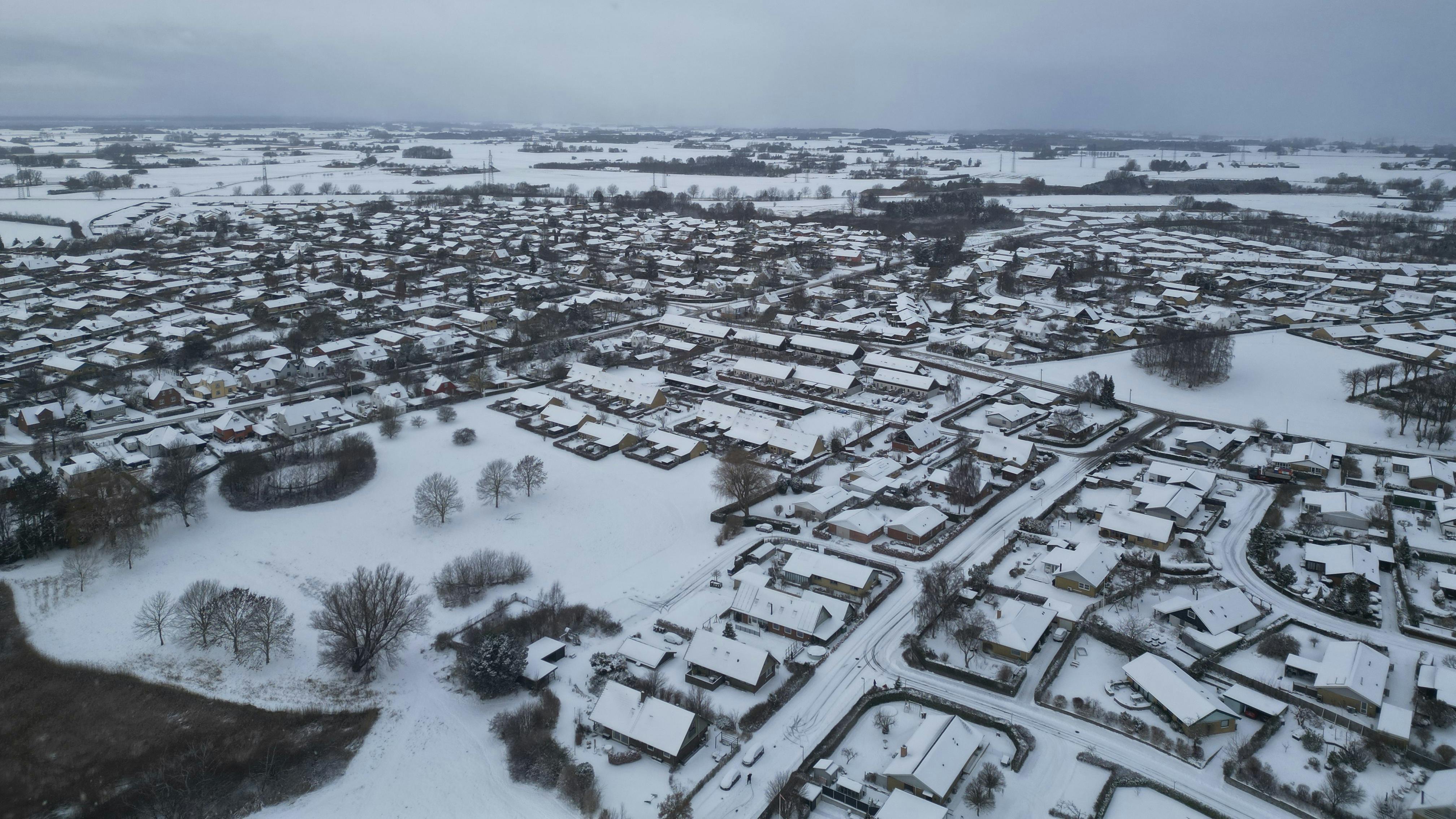 Sneklædt dansk by set fra luften, der illustrerer vintervejr med frost og snebyger varslet af DMI i den kommende uge