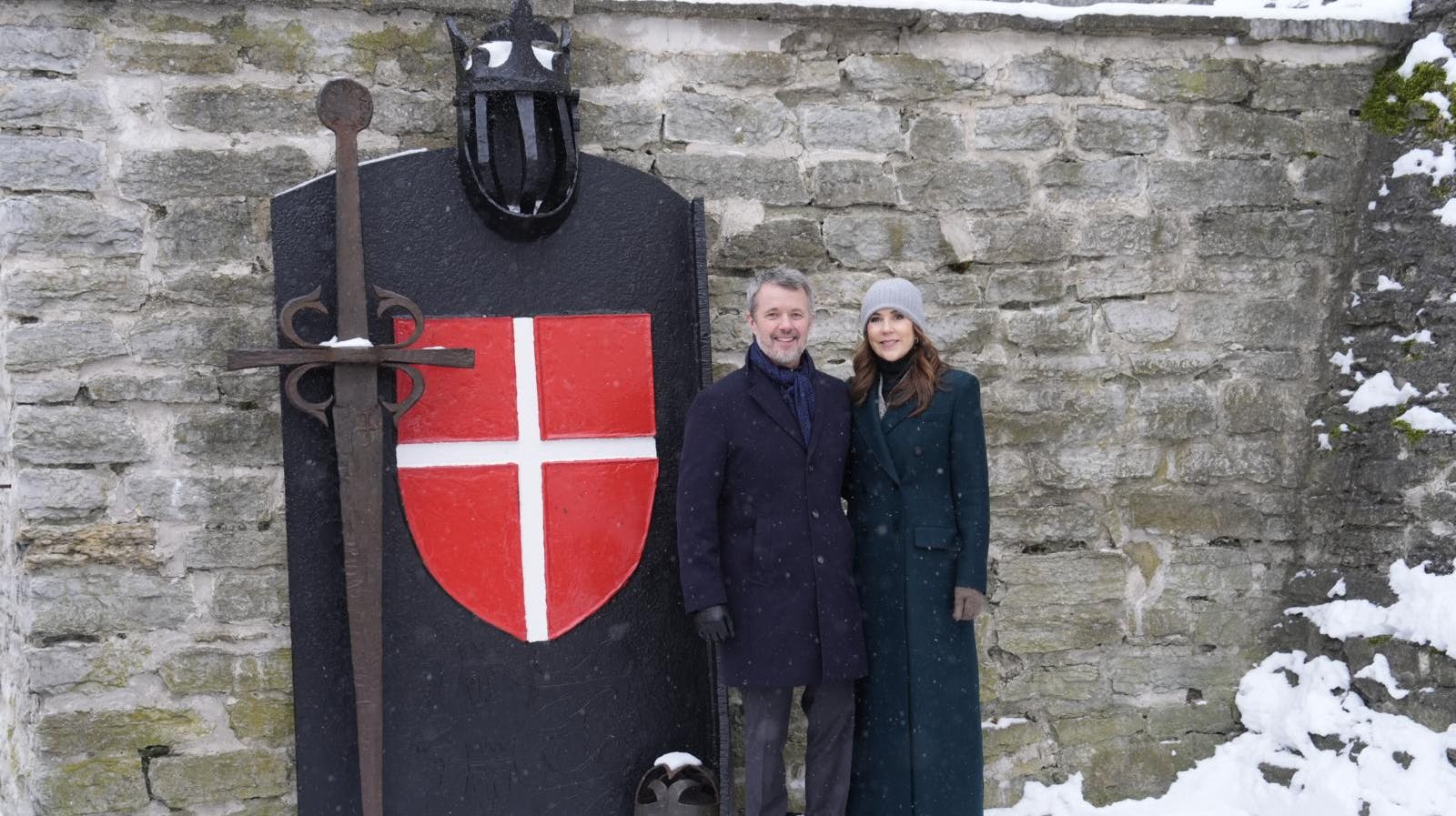 Kong Frederik og Dronning Mary er her fotograferet foran den historiske port prydet med Dannebrog i Tallinn. Besøget i Estland markerede de tætte historiske bånd, der ifølge legenden strækker sig helt tilbage til flagets fald fra himlen i 1219.