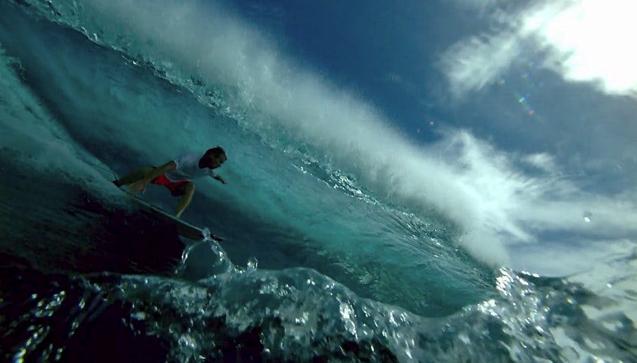 Omgivet af vand bevæger surferen sig fremad på sit bræt